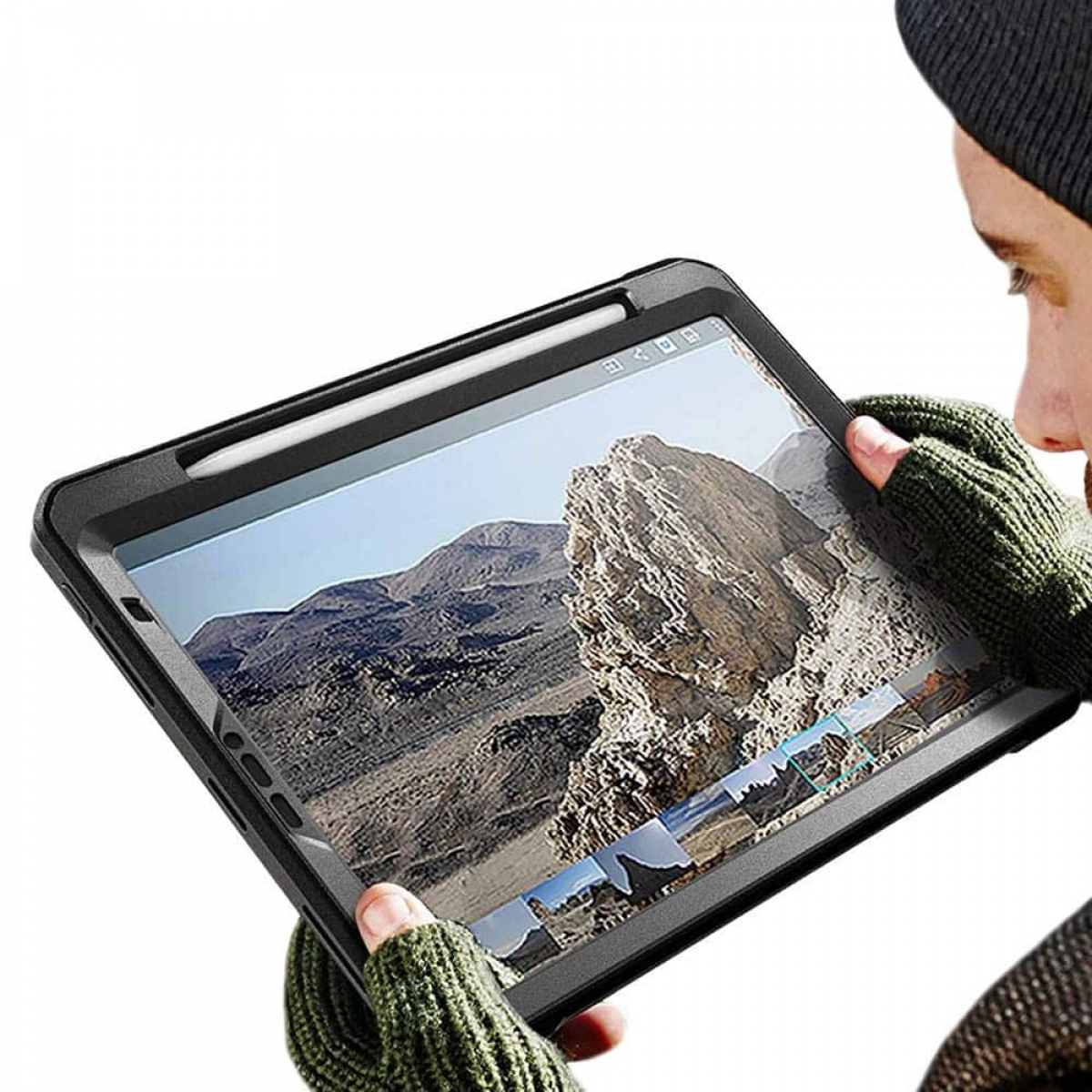Person hält Tablet in Hülle, benutzt Stift, vor Berglandschaft.