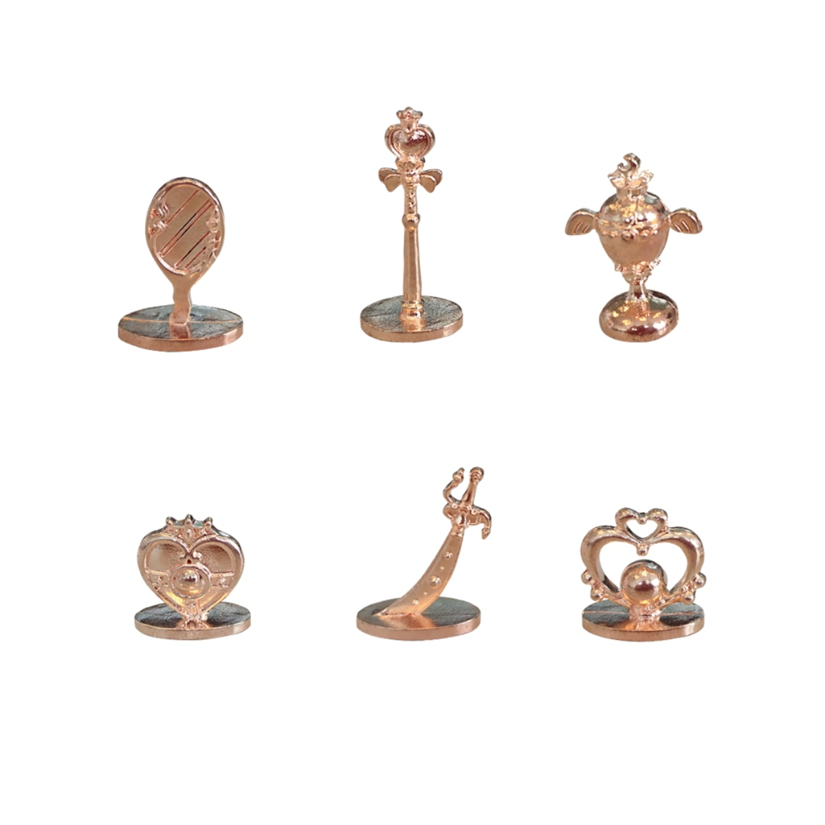 Sei pedine Monopoly color oro rosa su bianco. Varie forme, tra cui specchio, bacchetta, coppa, ecc.