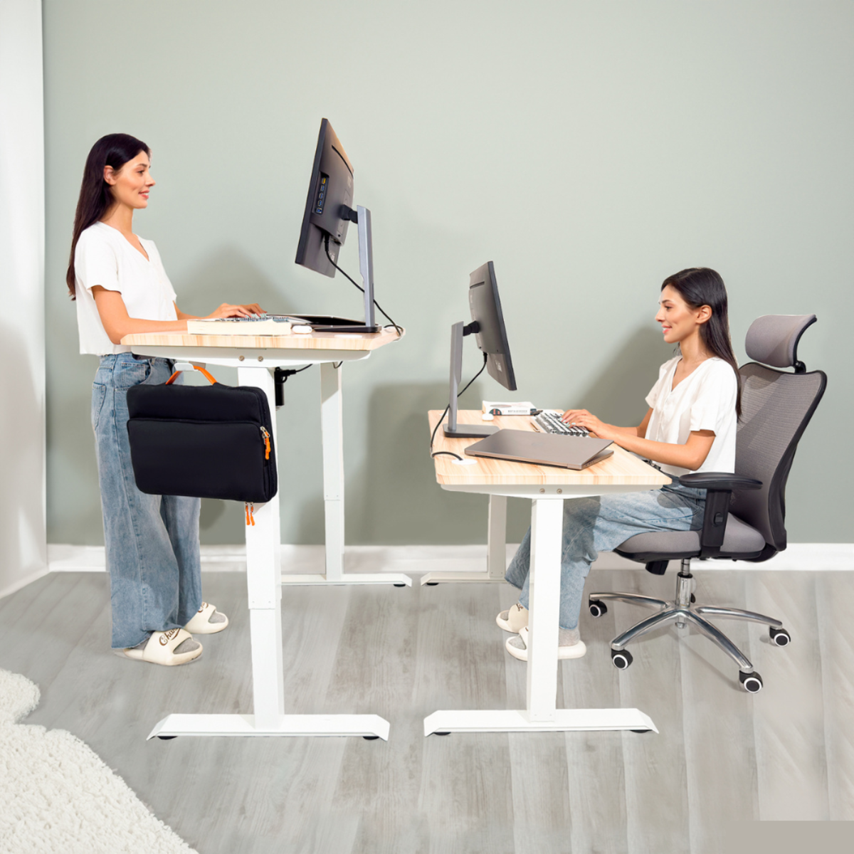 Dos mujeres trabajando en escritorios con computadoras. Una está de pie y otra sentada en una silla.
