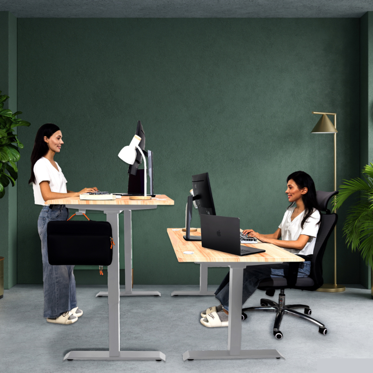 Dos mujeres en escritorios de pie en una oficina moderna, usando computadoras.
