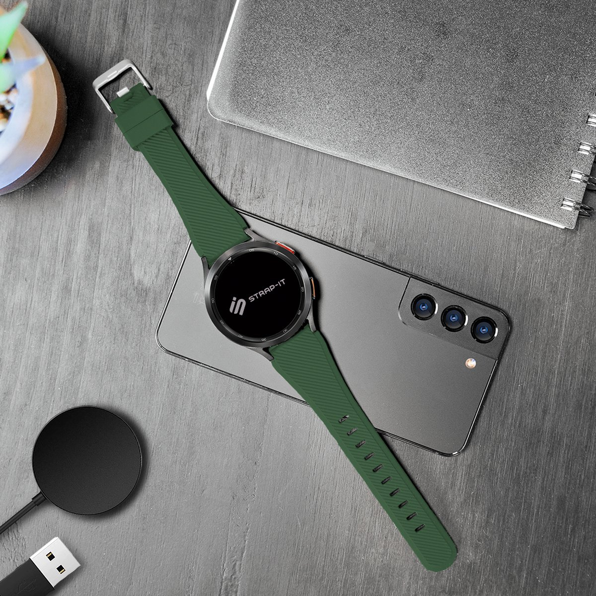 Grüne Smartwatch mit grünem Armband, die auf einem Telefon und einem Ladegerät liegt.