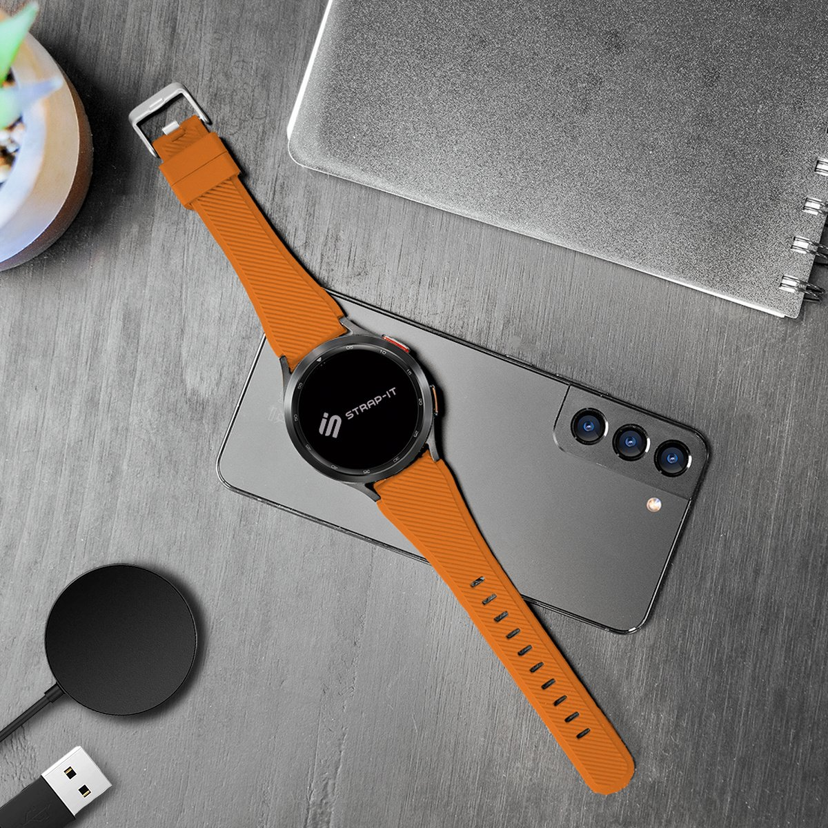 Orangenes Uhrenarmband mit Uhr. Die Uhr ist schwarz mit schwarzem Bildschirm. Auf dunklem Tisch.