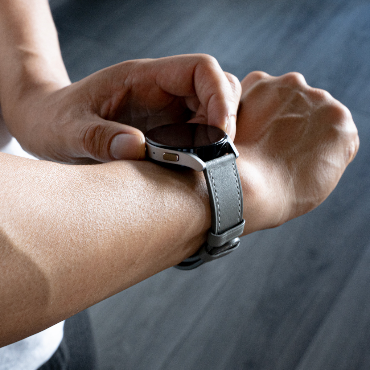 Eine Person trägt eine Smartwatch mit grauem Lederarmband.