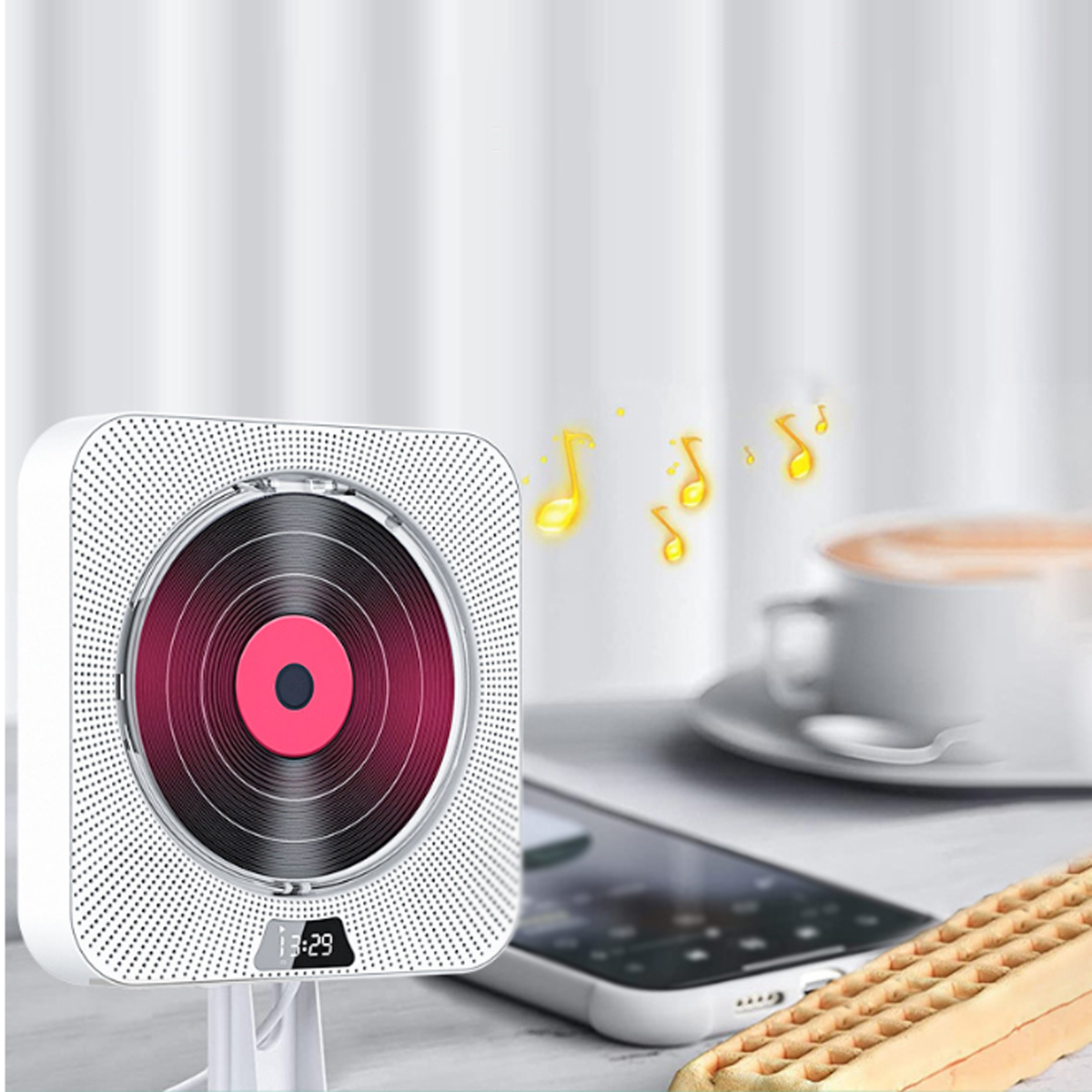 Ein weißer CD-Player mit Noten, neben einem Telefon, Kaffee und einer Waffel.