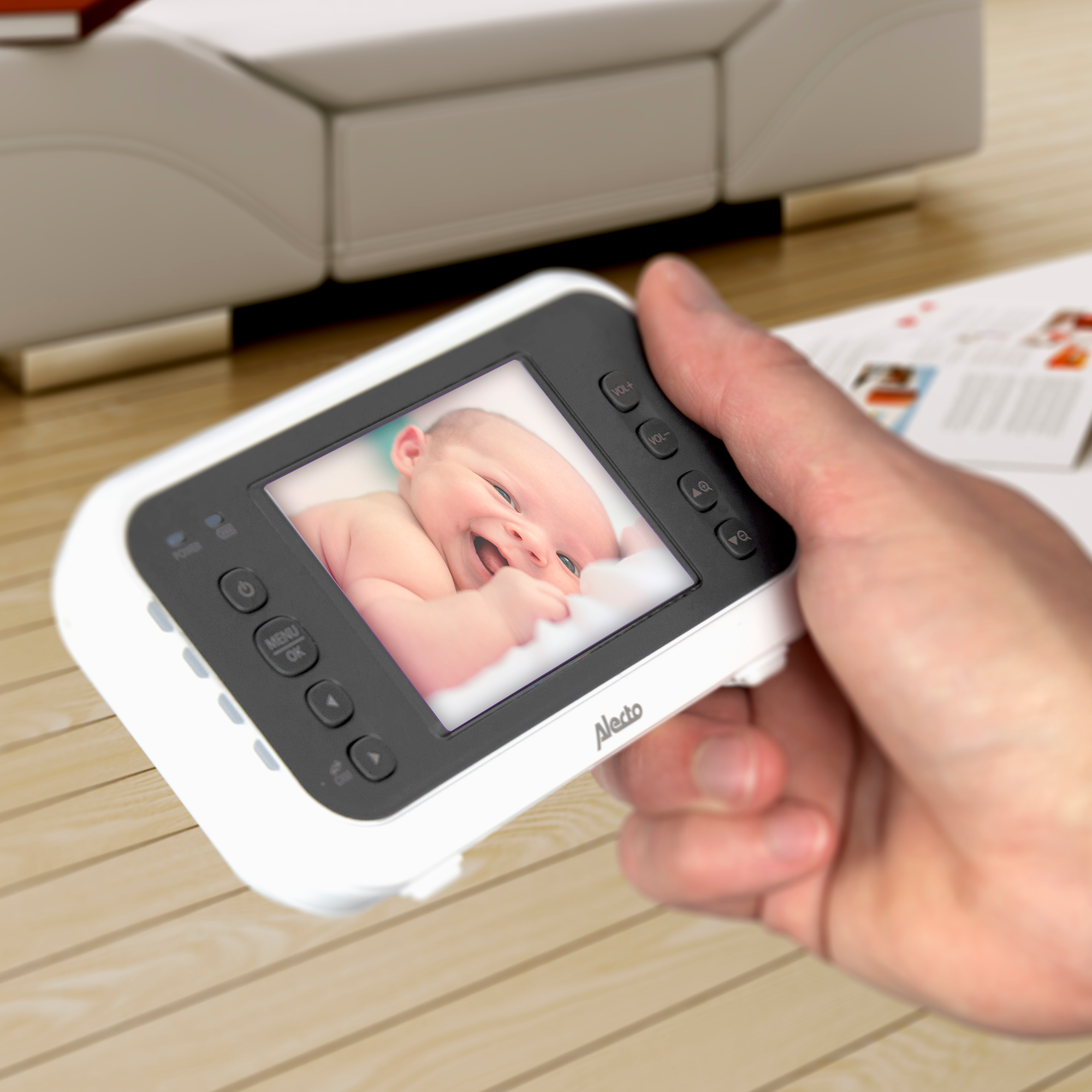 A baby monitor showing a baby, held by a hand.