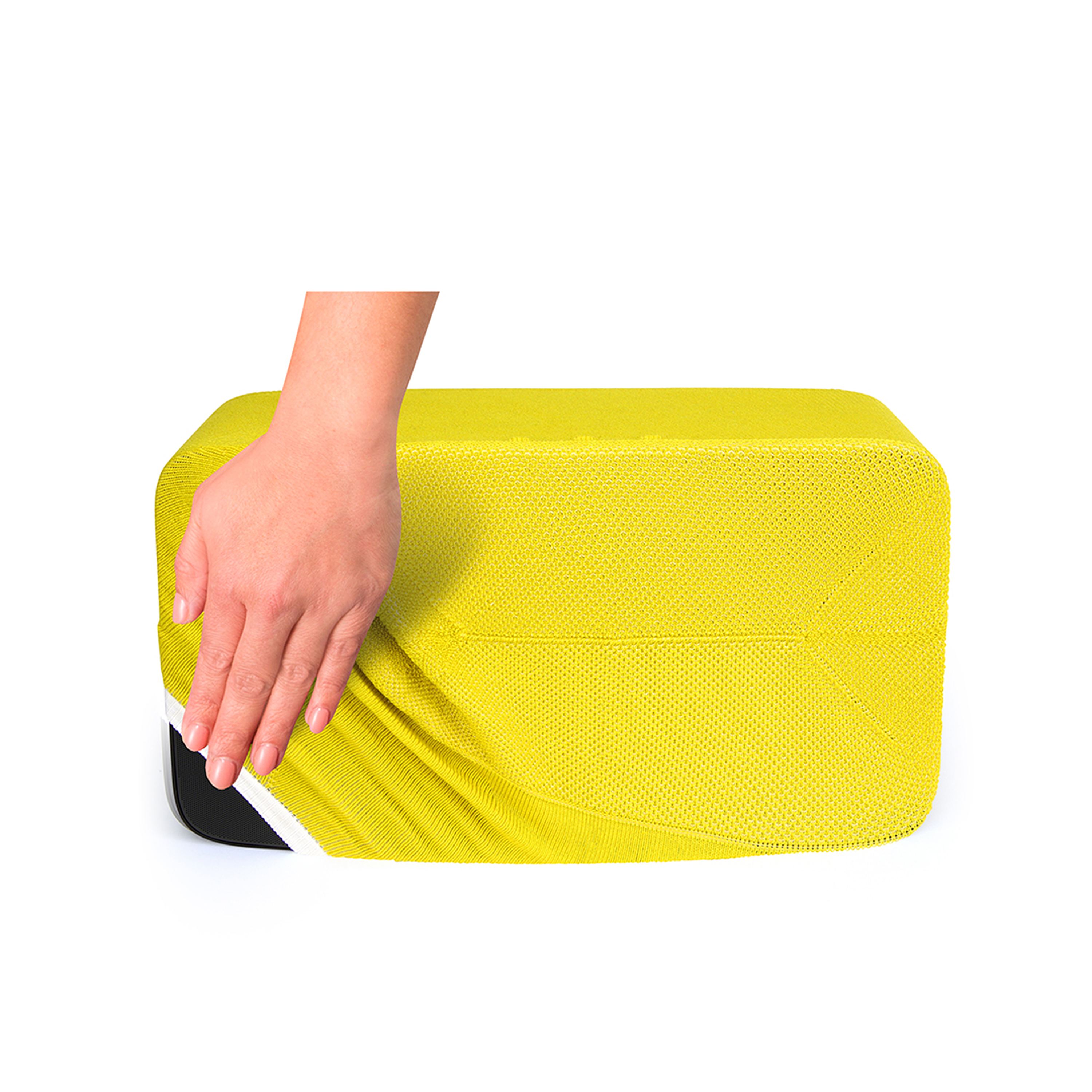 Une main recouvre un bloc de mousse jaune. Le bloc est sur une surface blanche.