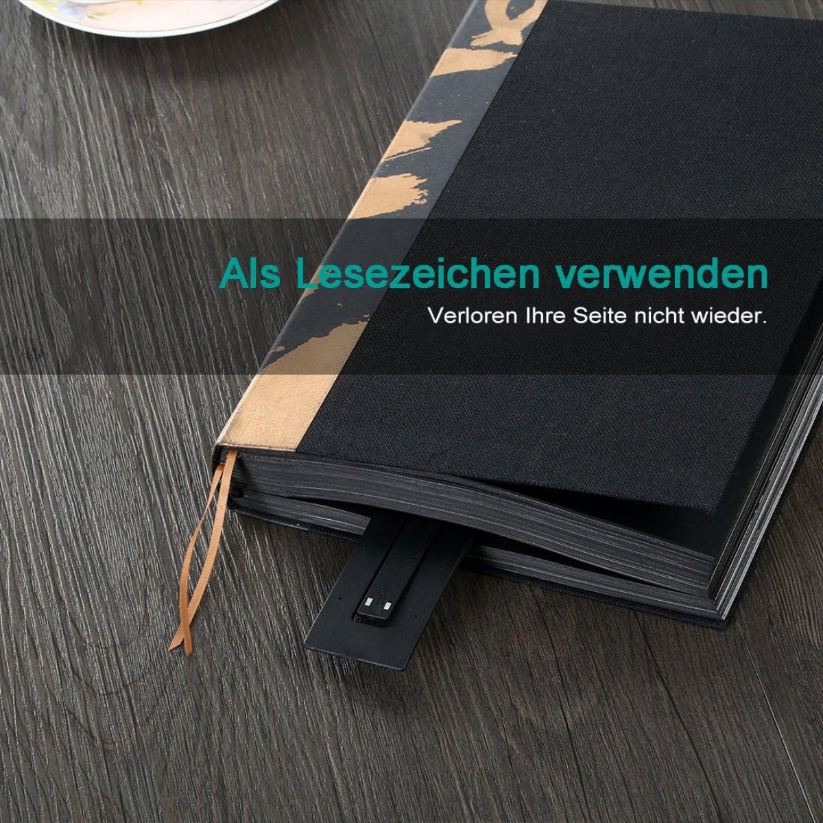 Offenes schwarzes Notizbuch mit einem Lesezeichen; Text auf Deutsch sagt, als Lesezeichen verwenden.