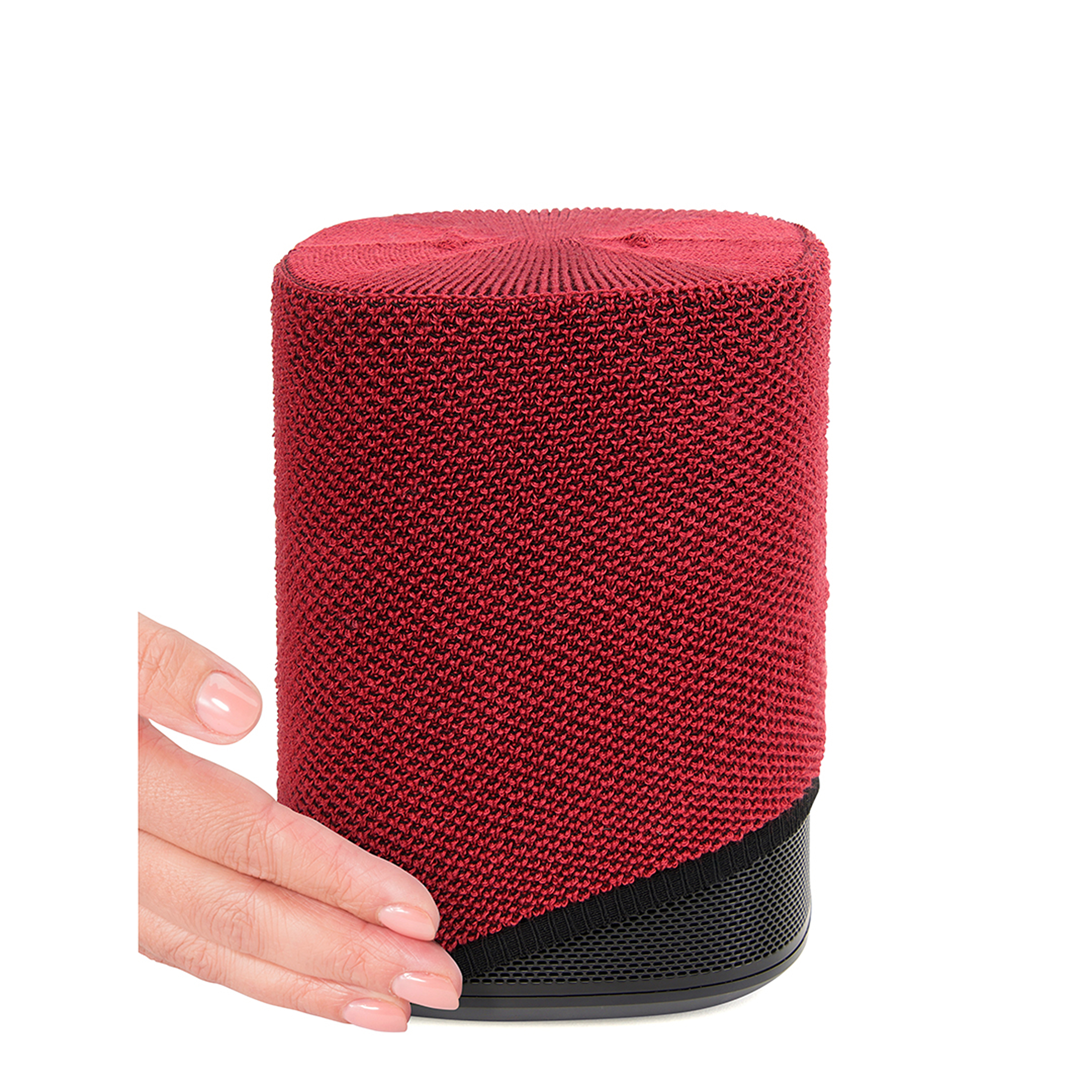 Un haut-parleur cylindrique rouge avec une base noire. Une main atteint pour ajuster le haut-parleur.