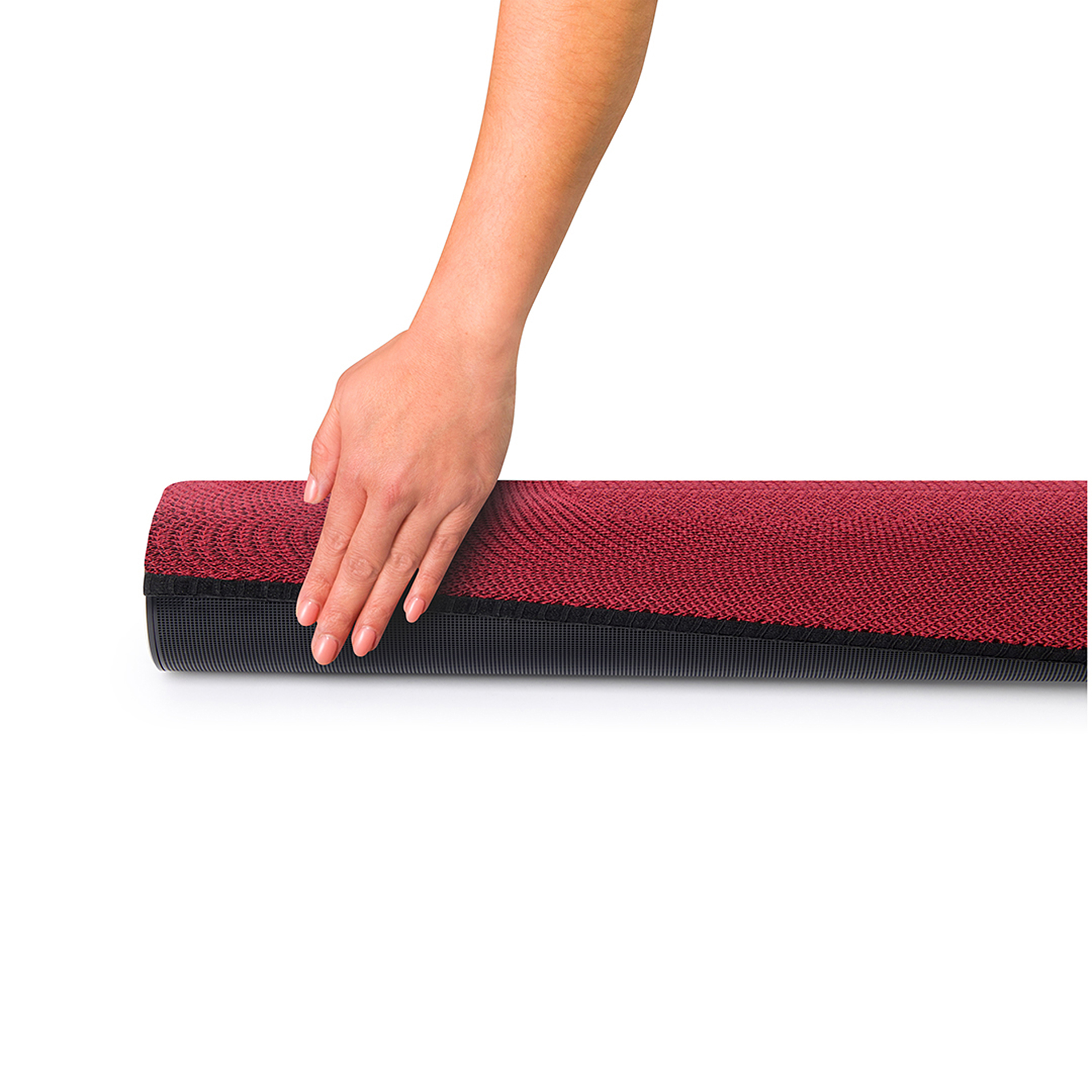 Een hand rolt een rood-zwarte yogamat op. De mat is gedeeltelijk opgerold.