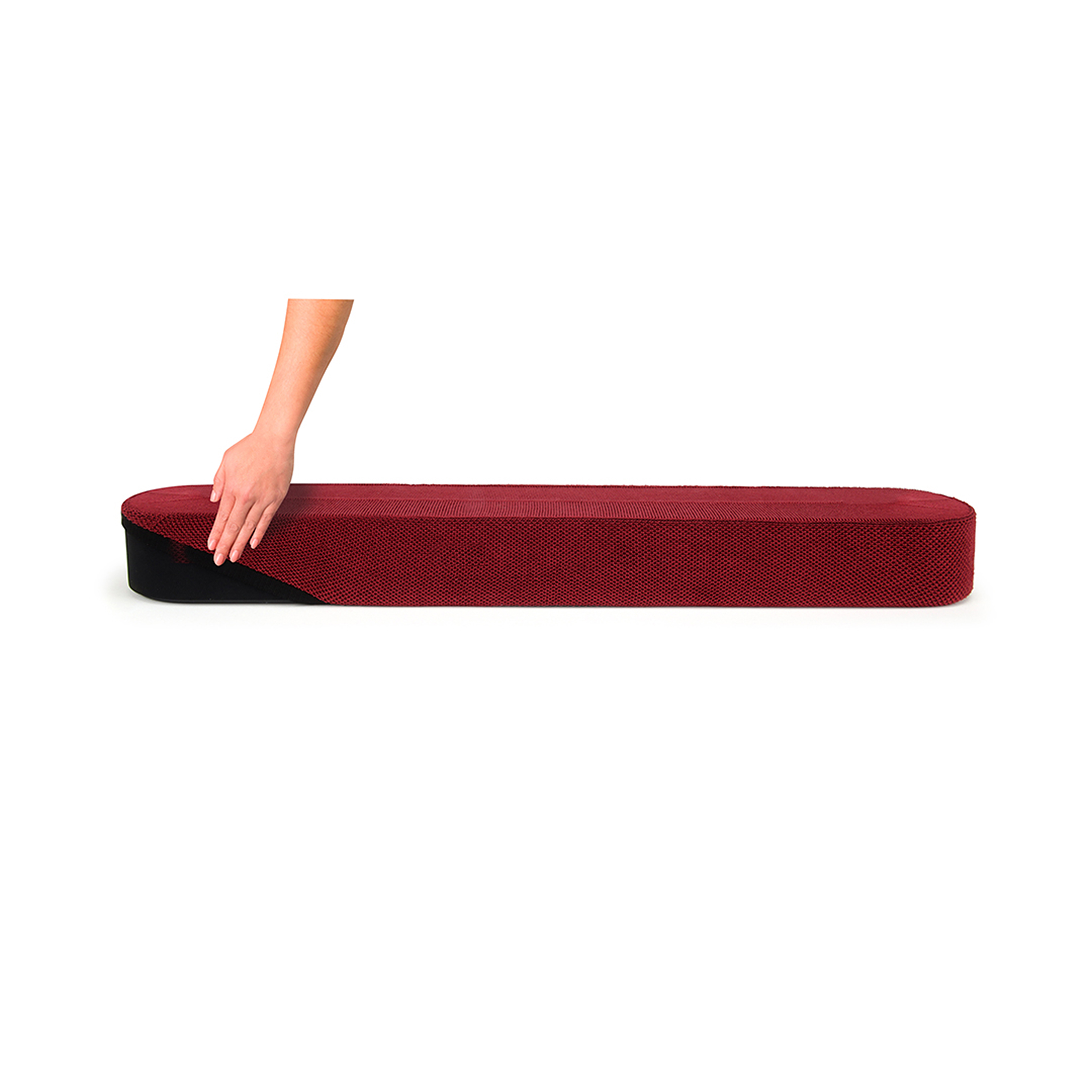 Une main recouvre un banc rembourré rouge, base noire, fond blanc, vue de côté.