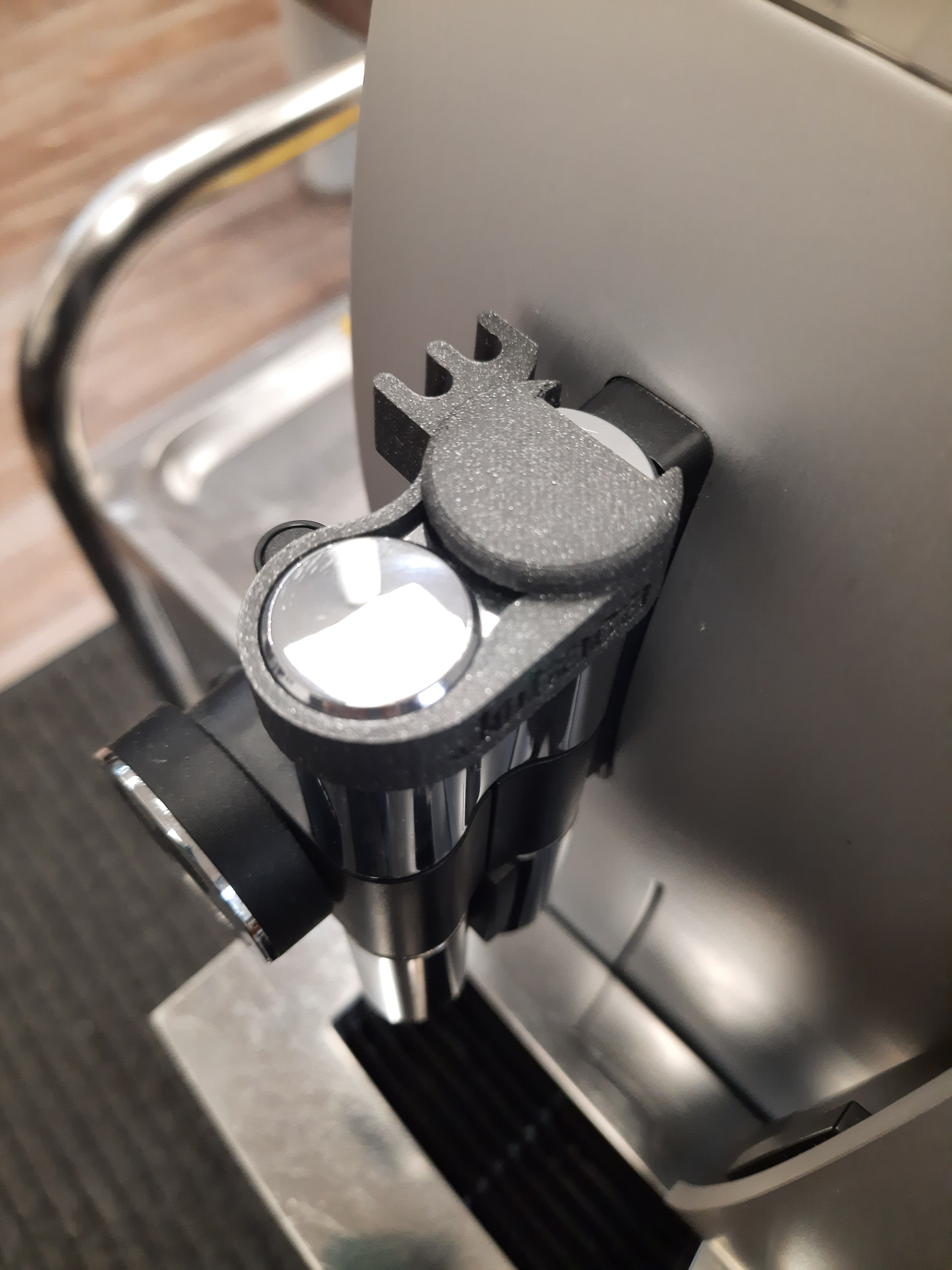 Nahaufnahme eines schwarzen Kaffeeautomatenaufsatzes. Es hat einen silbernen Knopf und eine Hirschform.