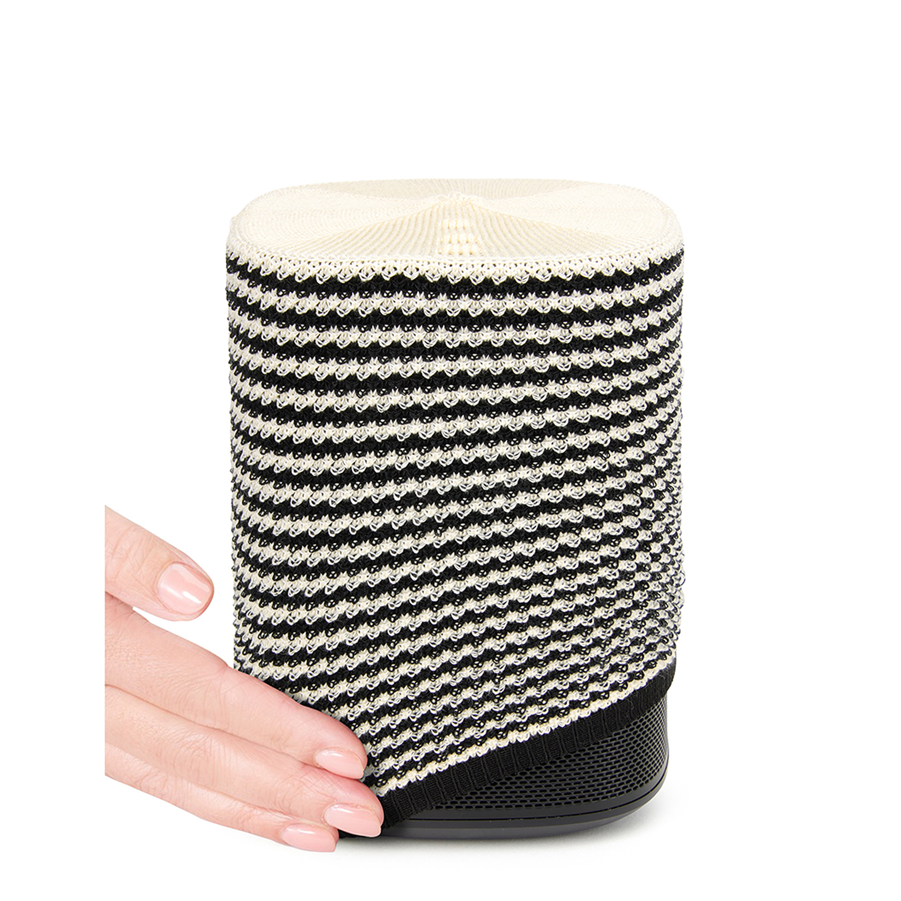 Un haut-parleur à motifs noir et blanc tenu par une main, isolé sur fond blanc.