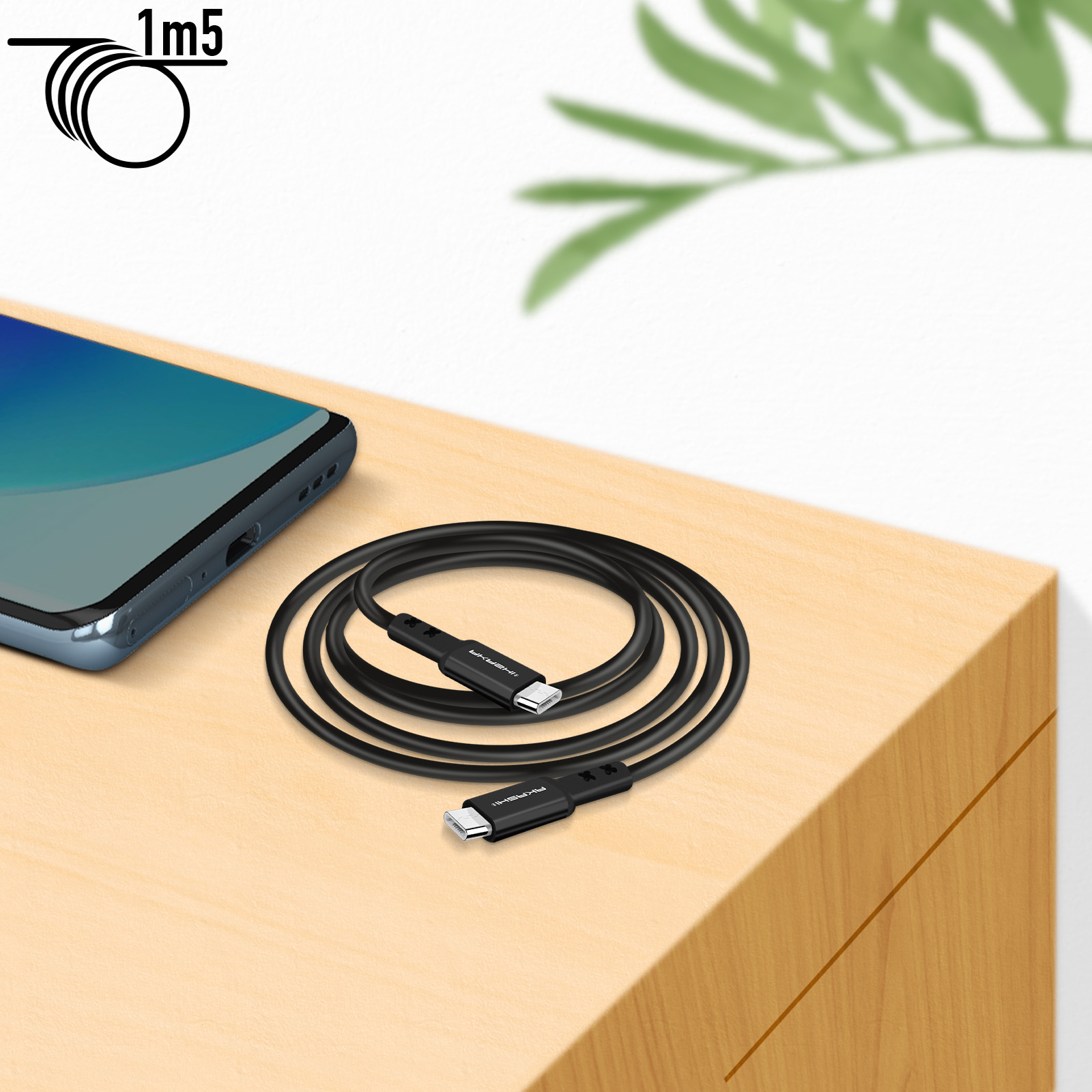 Un cavo USB-C nero arrotolato su una superficie di legno, con un telefono cellulare sullo sfondo.