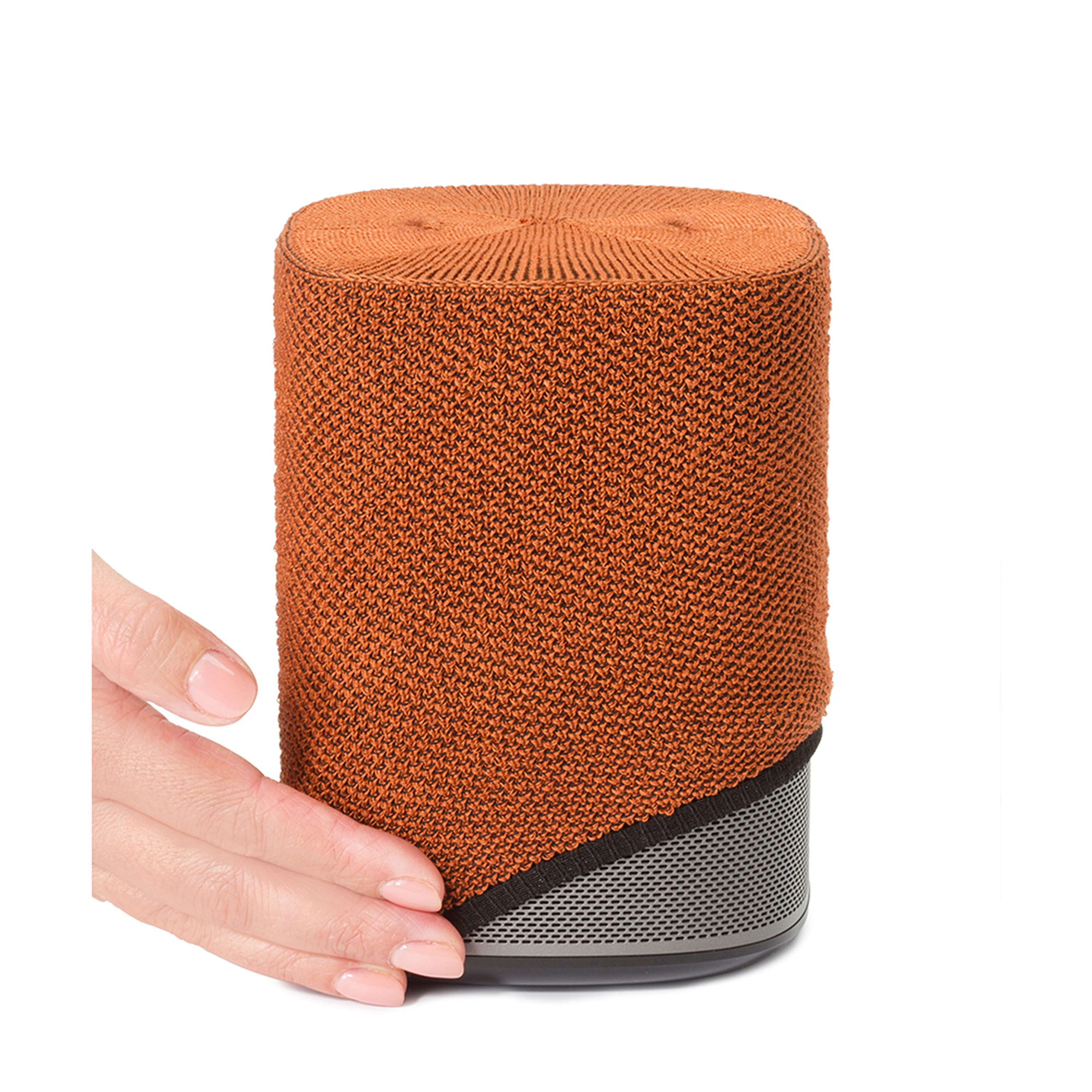 Une main tient un haut-parleur orange et cylindrique avec une base noire et argentée.