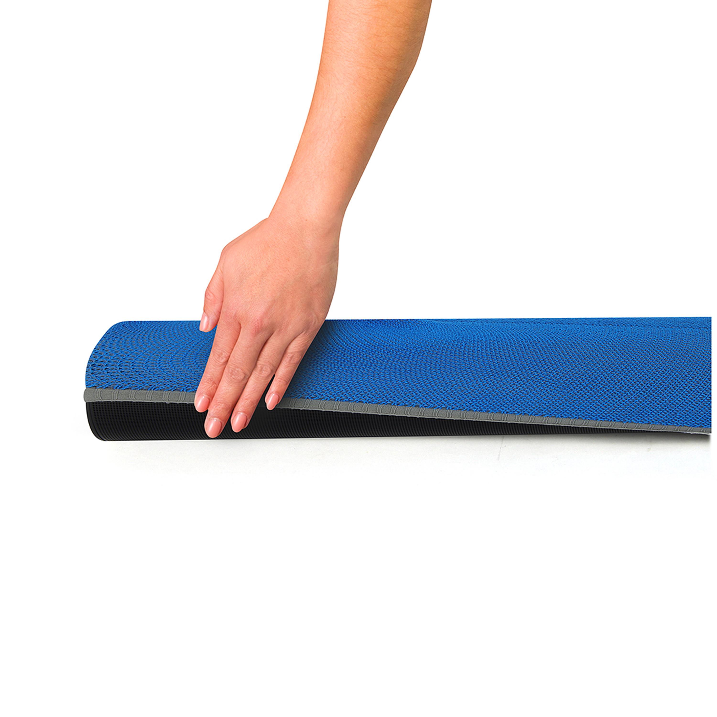 Een hand rolt een blauwe mat met een zwarte onderkant uit op een witte achtergrond.