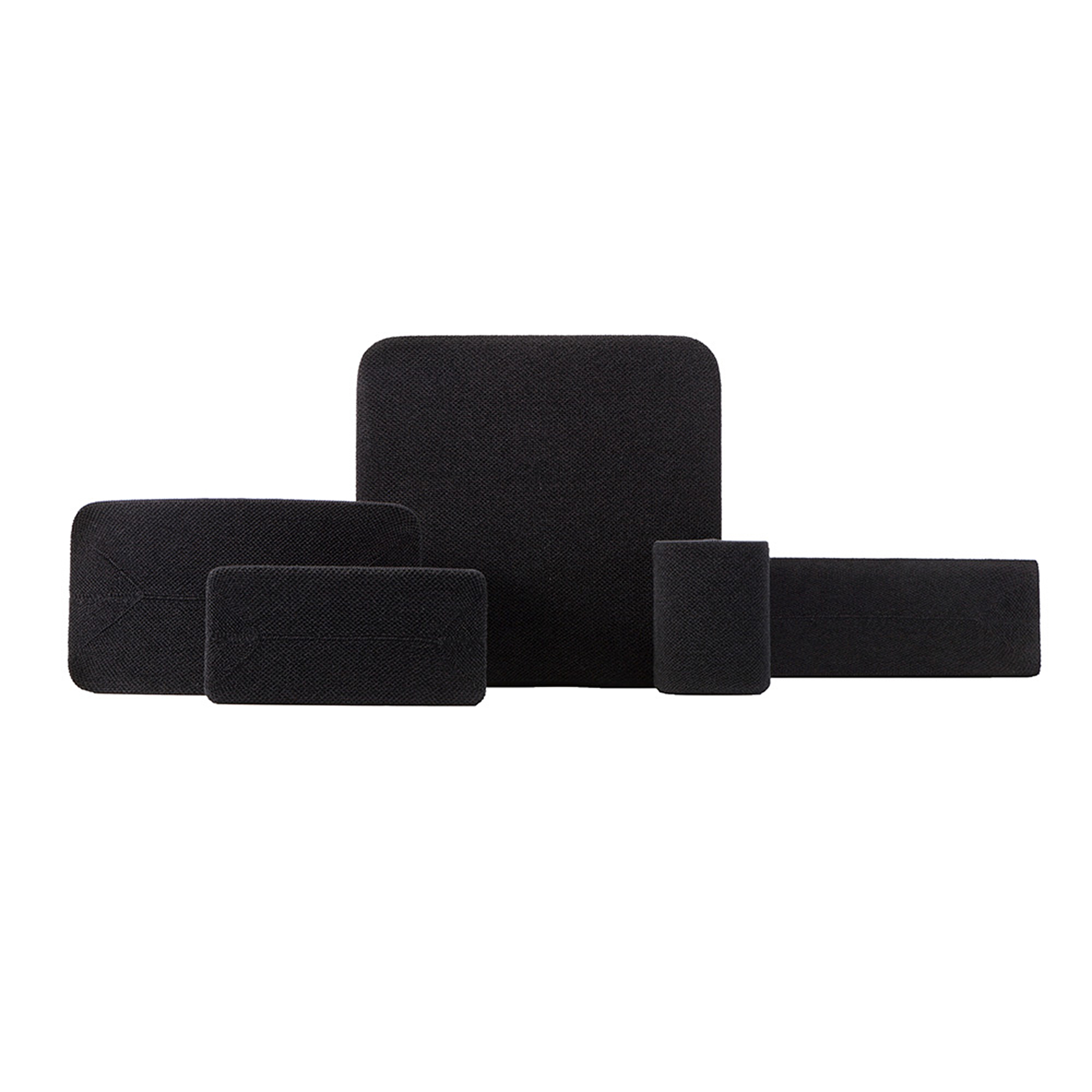 Cinq coussinets en mousse noirs de différentes formes et tailles, disposés sur une surface blanche.