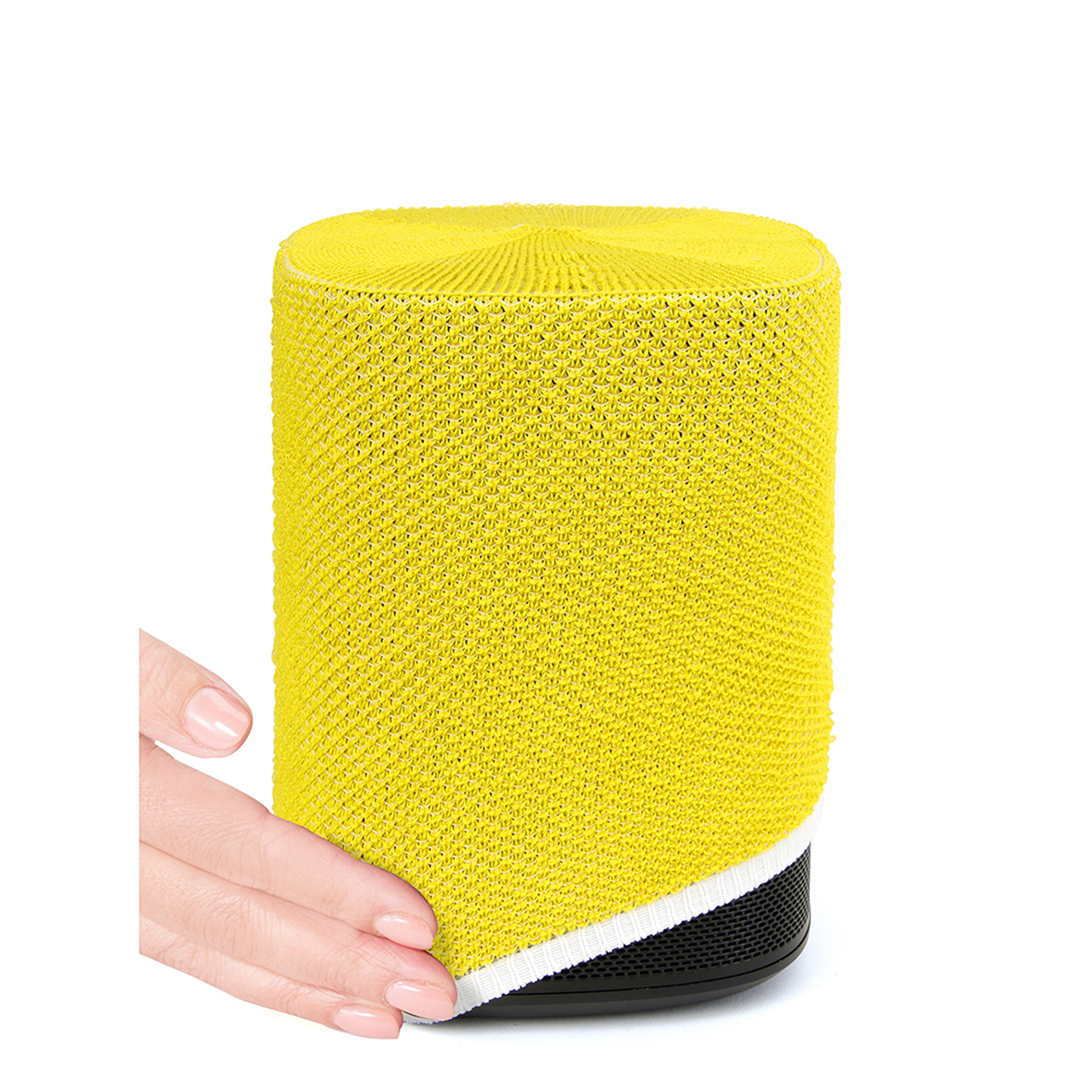 Une main couvrant un haut-parleur jaune avec une base noire et une bordure blanche.
