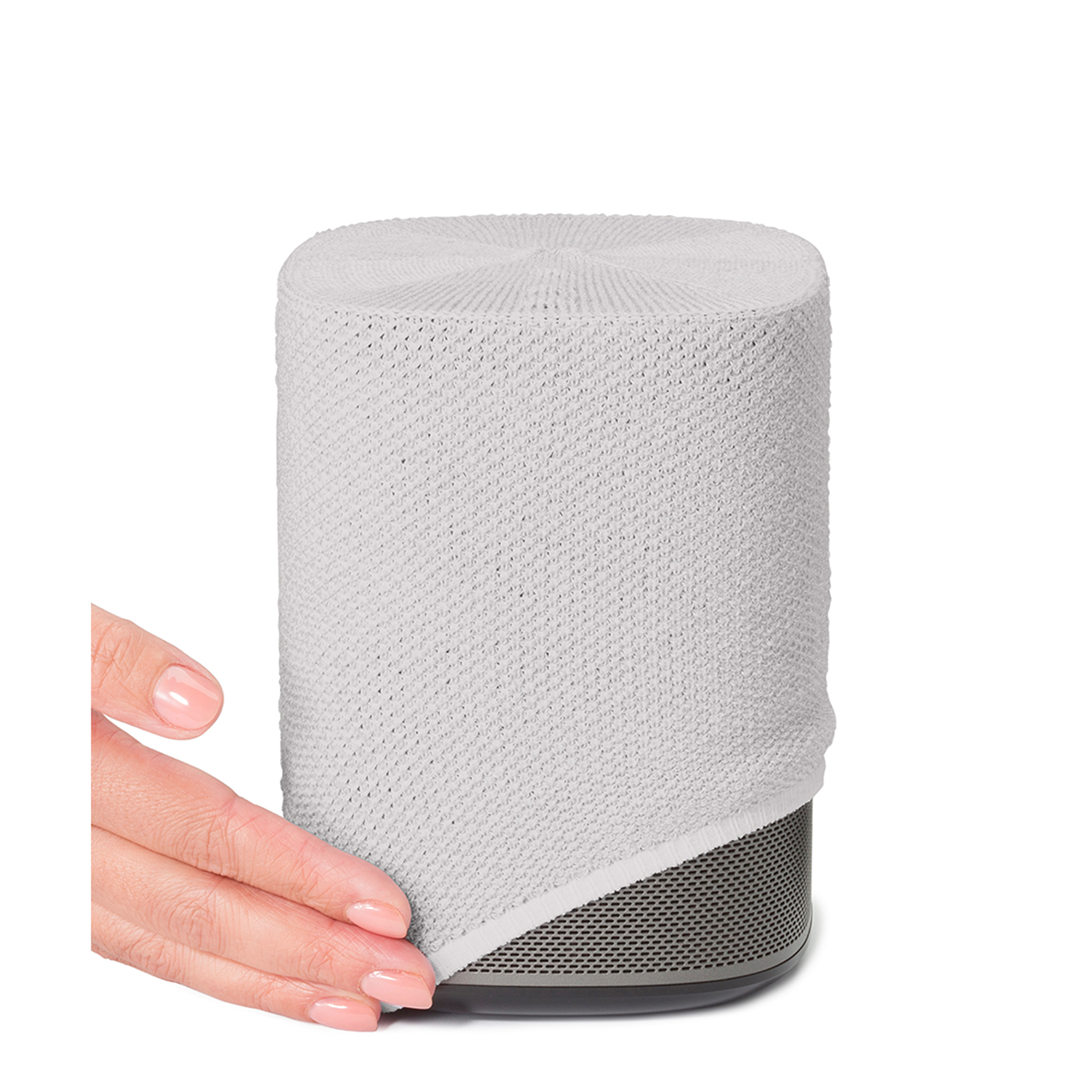 Une main tenant une housse en tricot blanc sur un haut-parleur. Le haut-parleur a une base noire.