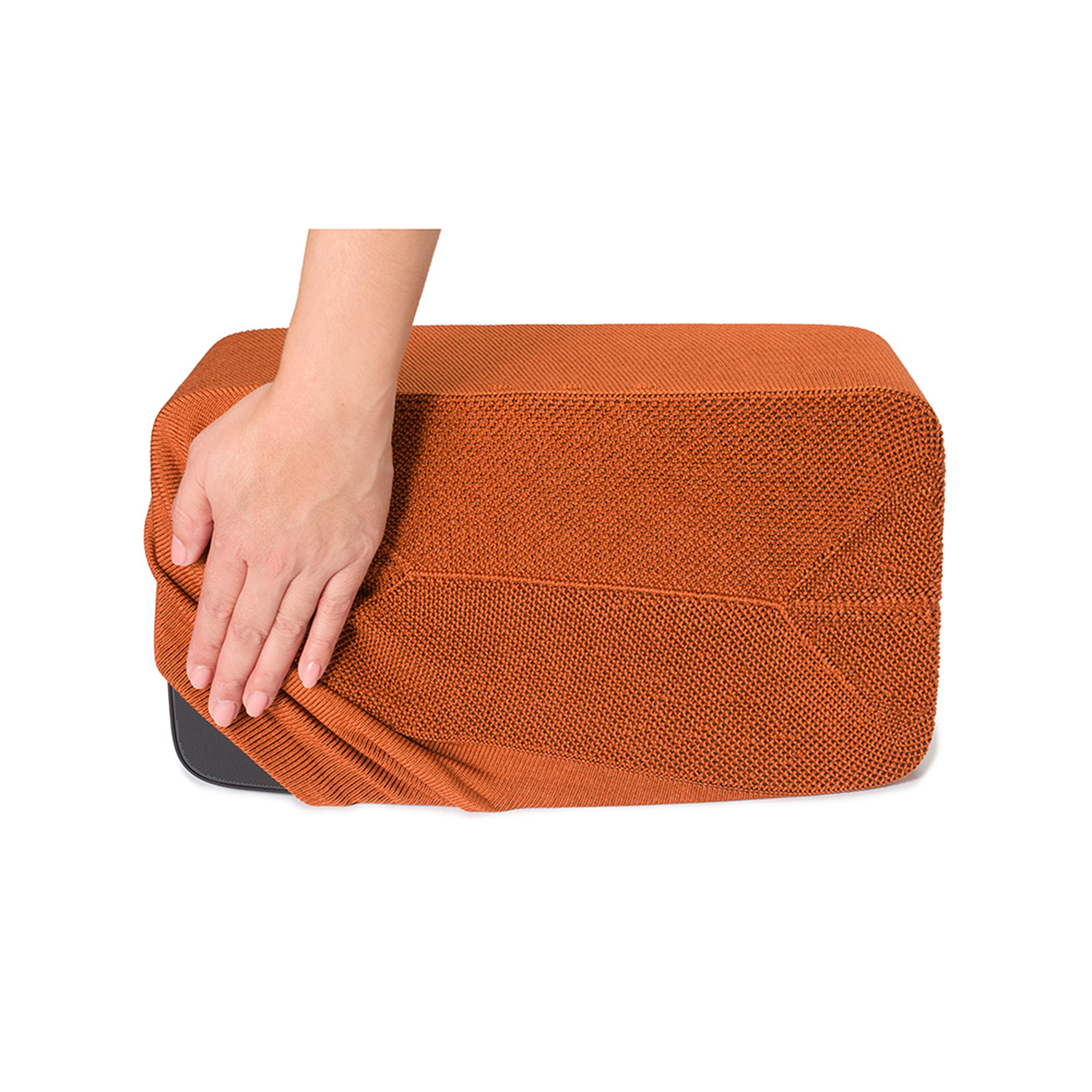 Une main plaçant une housse en tissu sur un objet rectangulaire.