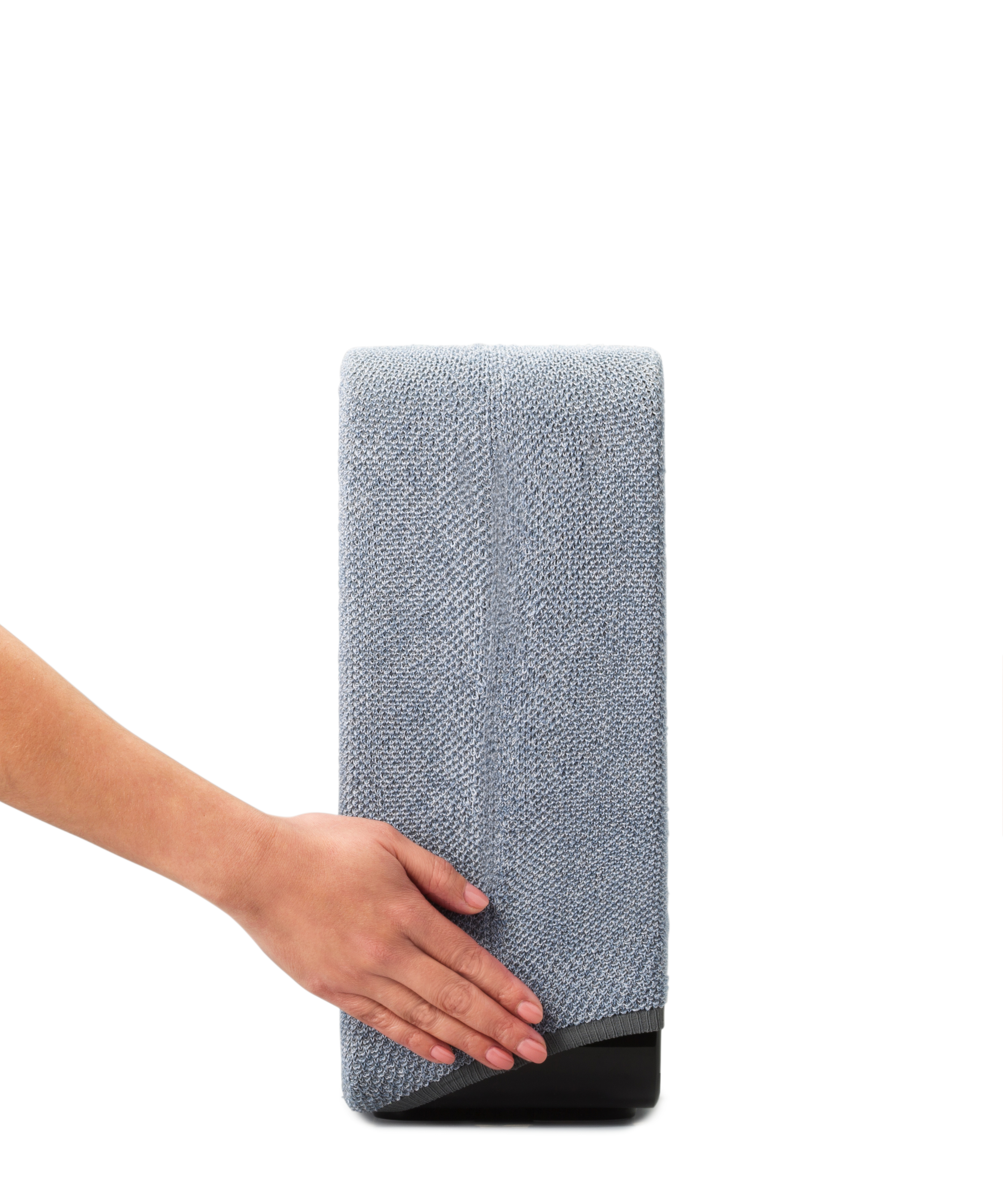 Haut-parleur gris tenu par une main, avec une base noire.