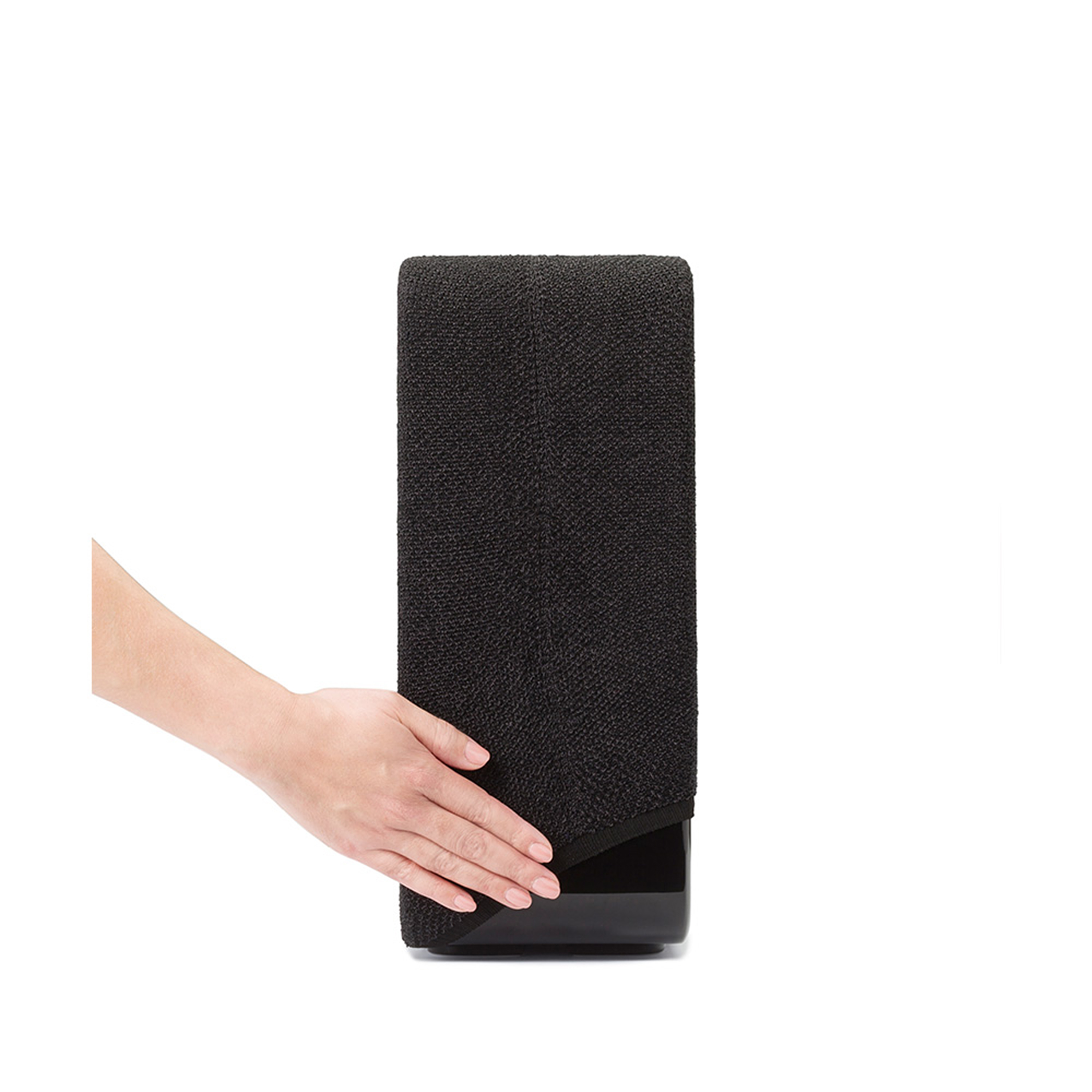 Une main tient un objet noir texturé sur un fond blanc.