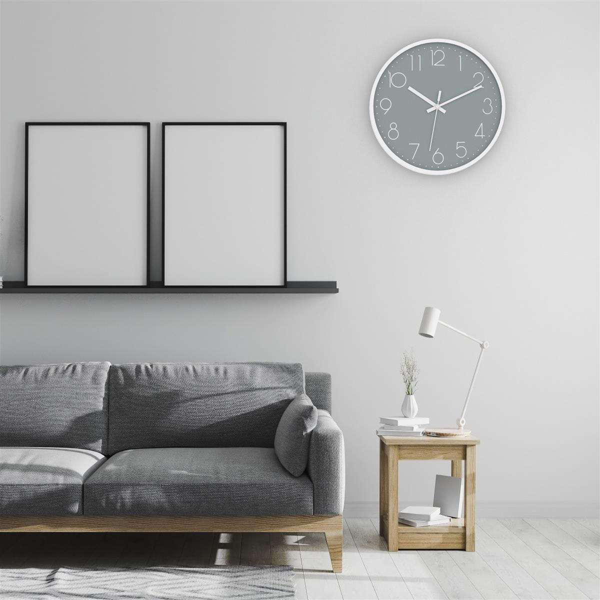 Wohnzimmer mit Sofa, Uhr und gerahmten Bildern an der Wand und einem Holztisch.