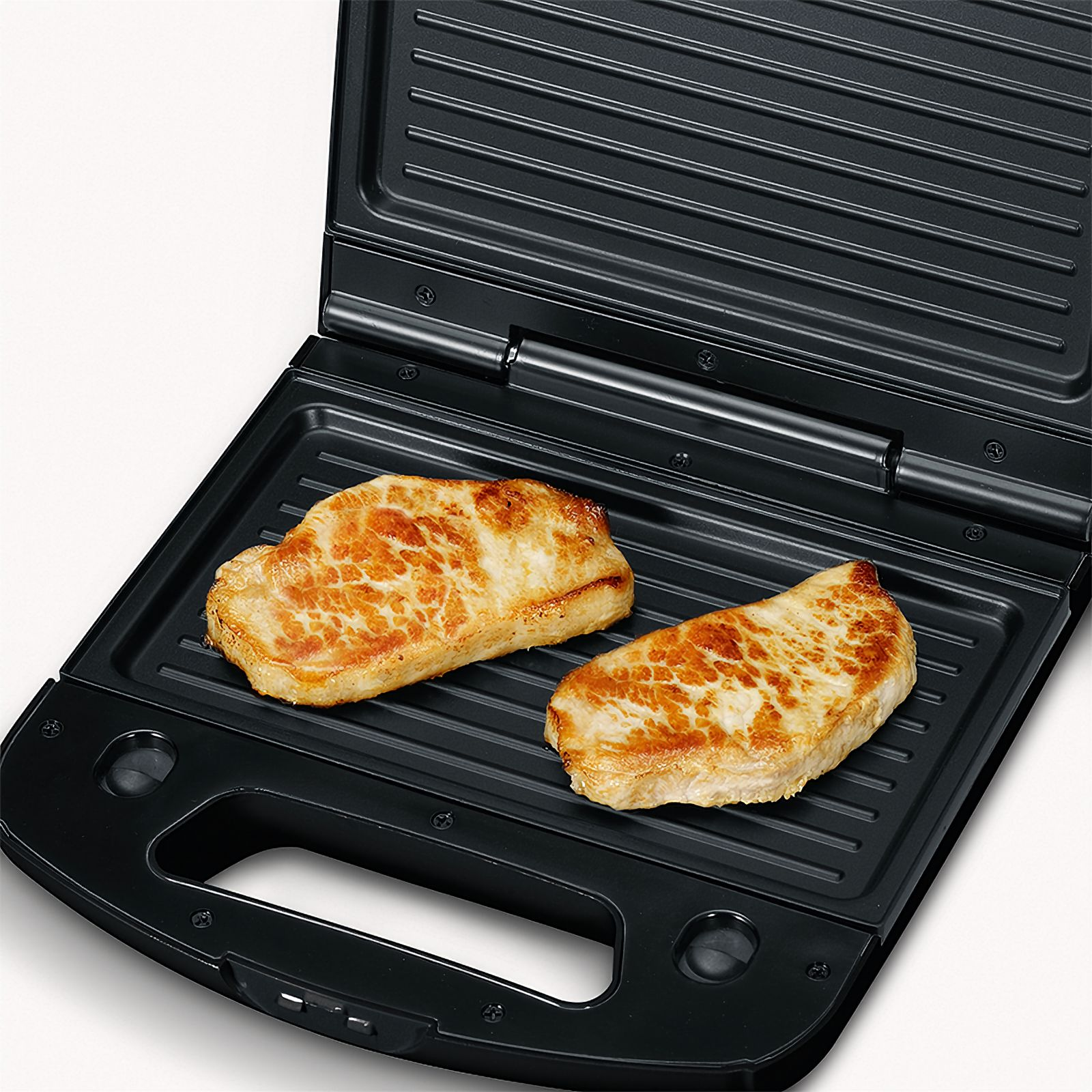 Czarny grill z dwoma kawałkami mięsa na grillu, widok z góry.