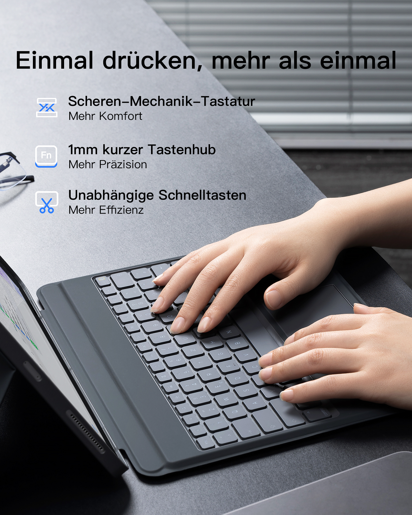 Hände tippen auf einer grauen Tastatur, daneben ein Tablet.