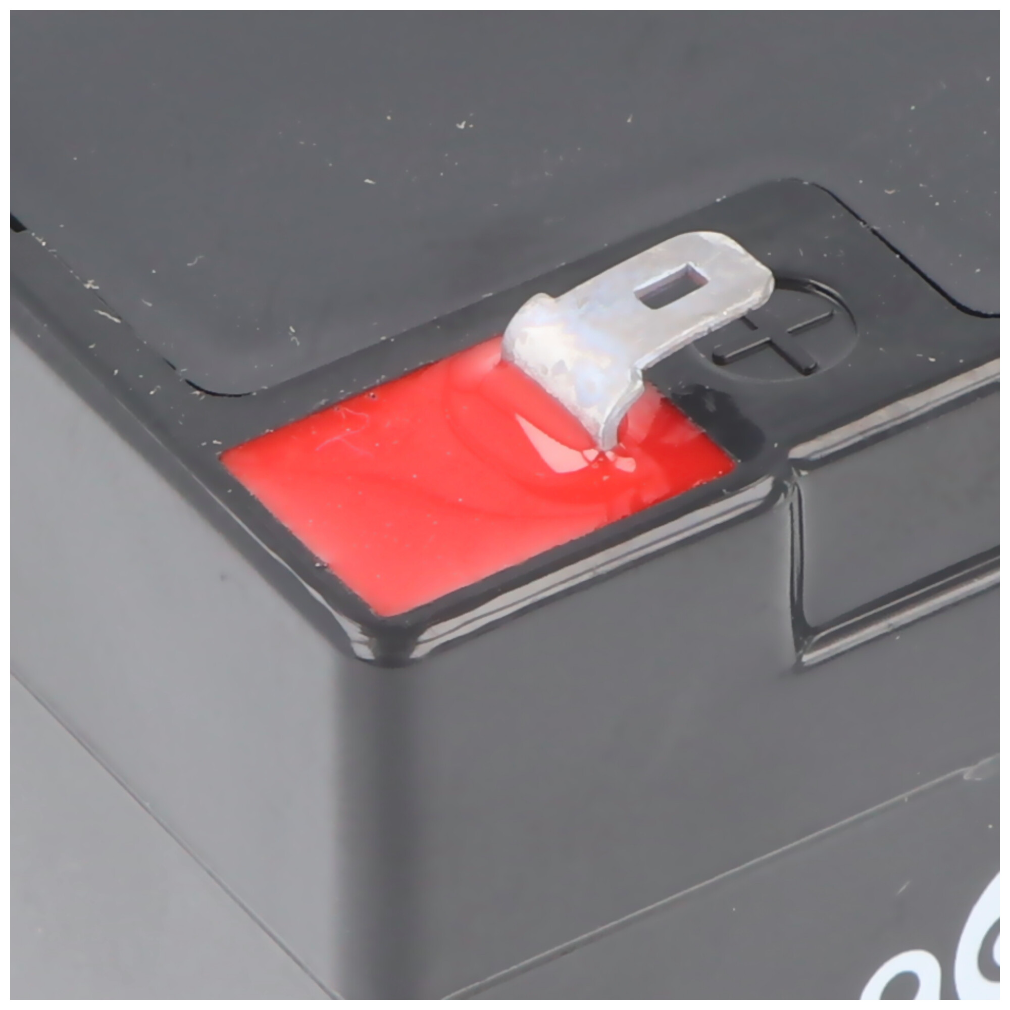 Nahaufnahme einer schwarzen Batterie mit rotem Anschluss und Metallverbinder.