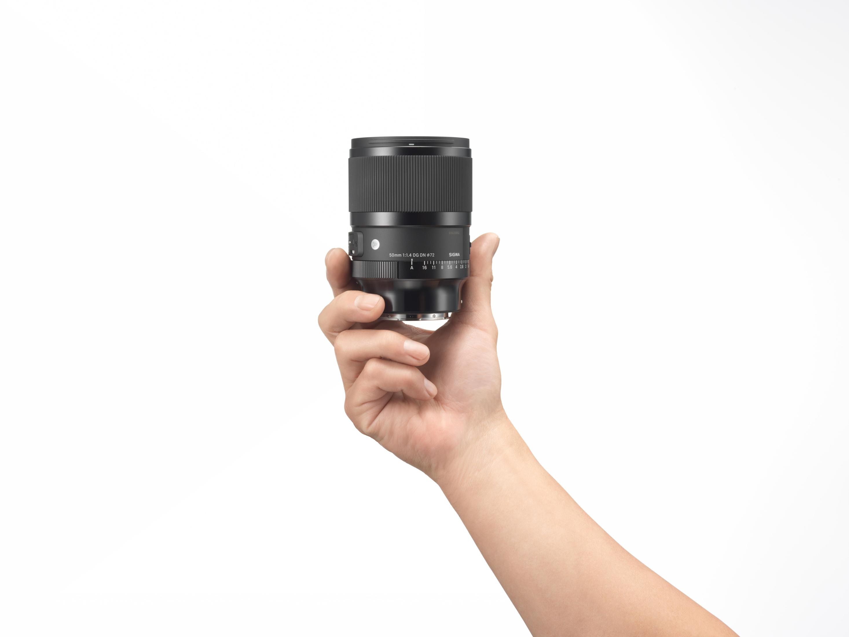 Een hand die een cameralens vasthoudt. De achtergrond is wit. De lens is zwart. De camera is zwart.