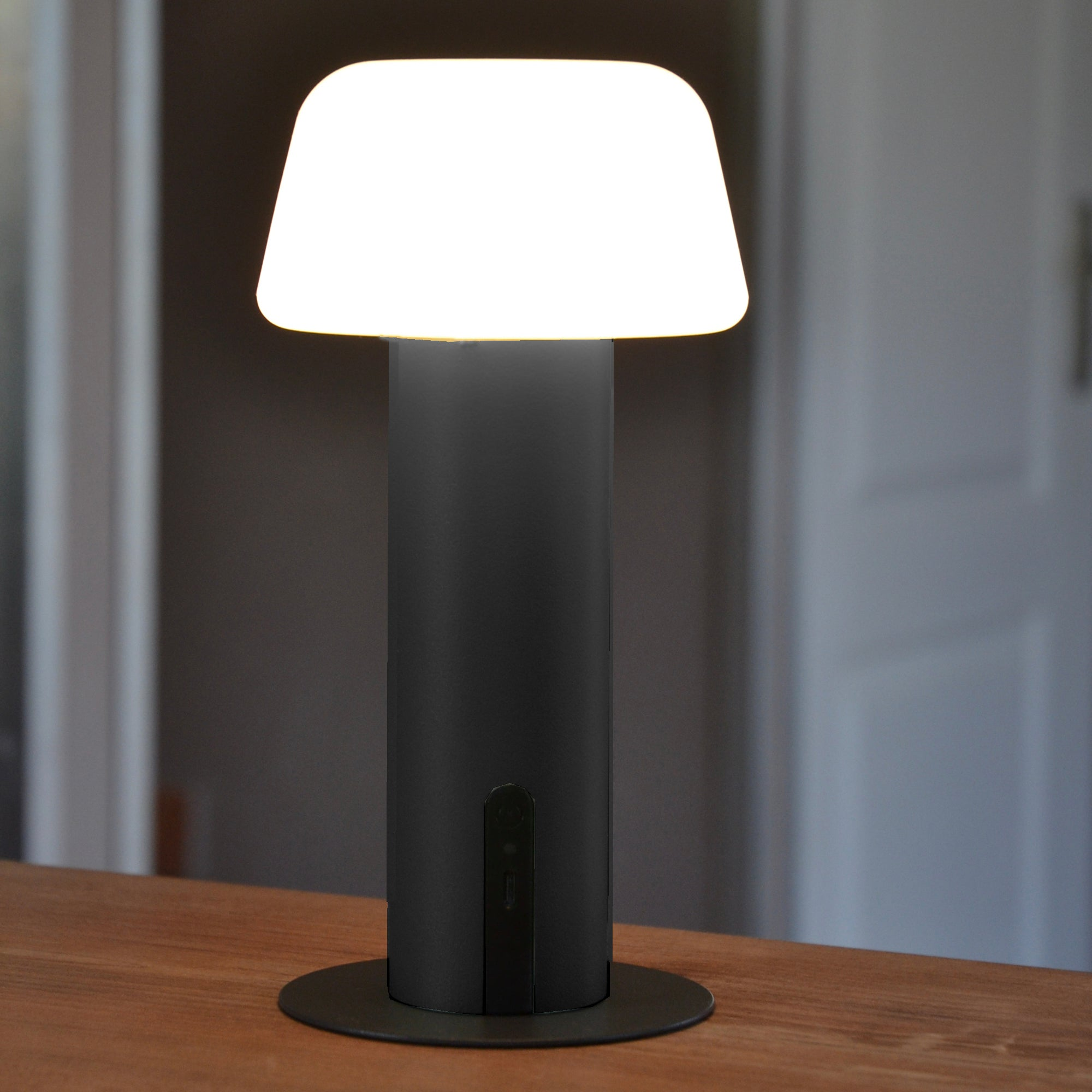 Schwarz-weiße Tischlampe mit leuchtendem, rechteckigem Schirm, freigestellt auf weißem Grund.