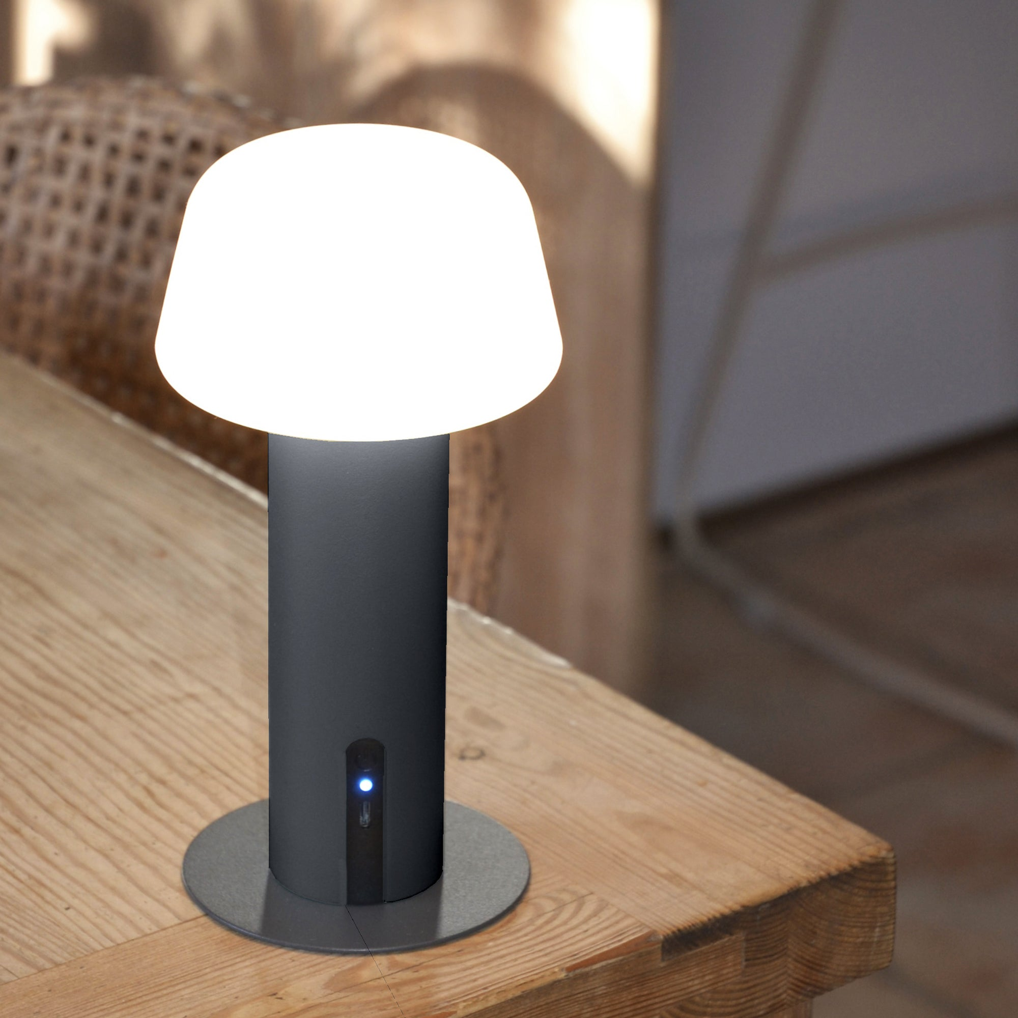 Dunkelgraue Lampe auf einem Holztisch. Weißes Licht oben.