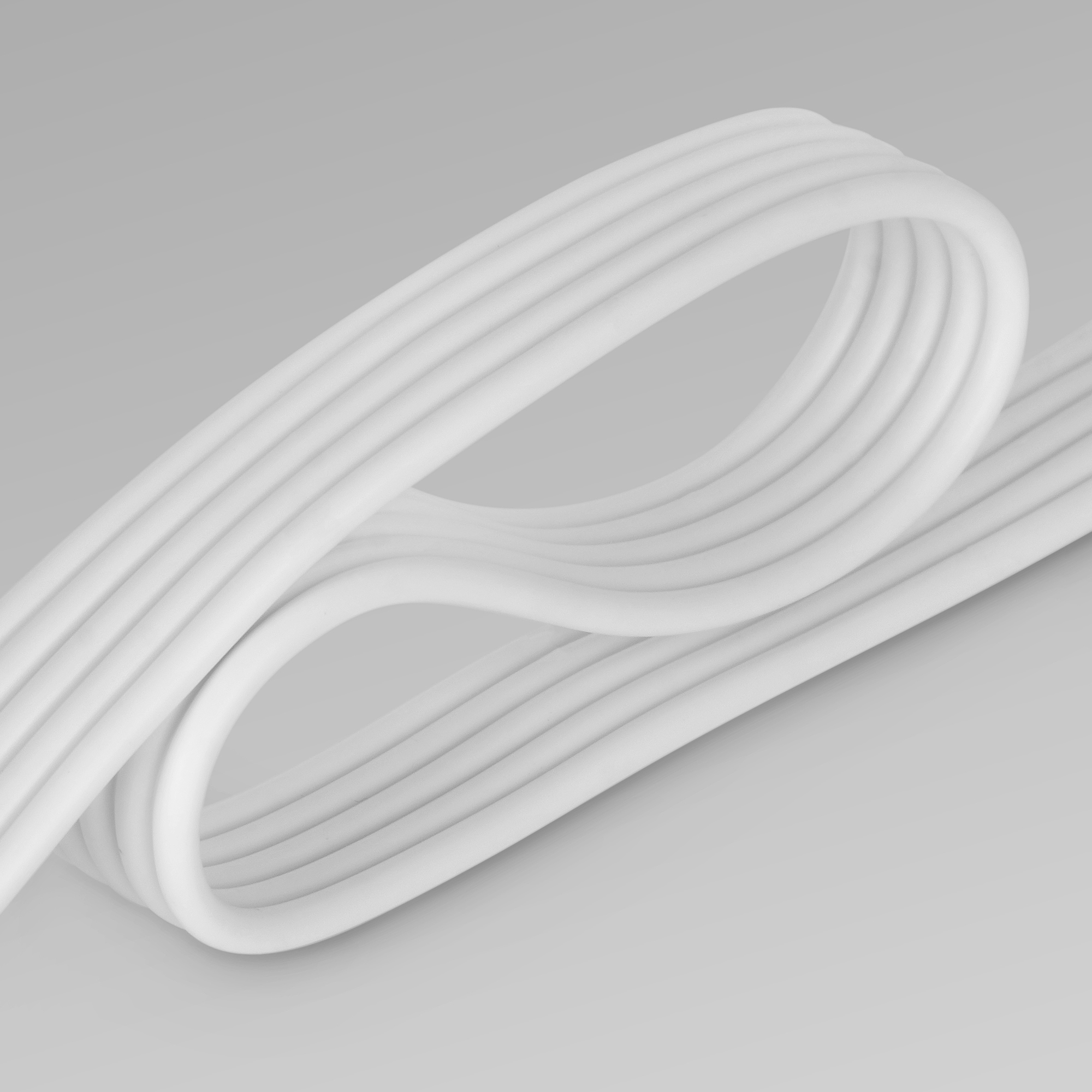 Zakrzywiony biały kabel ułożony na szarej powierzchni, pokazujący kształt kabla.