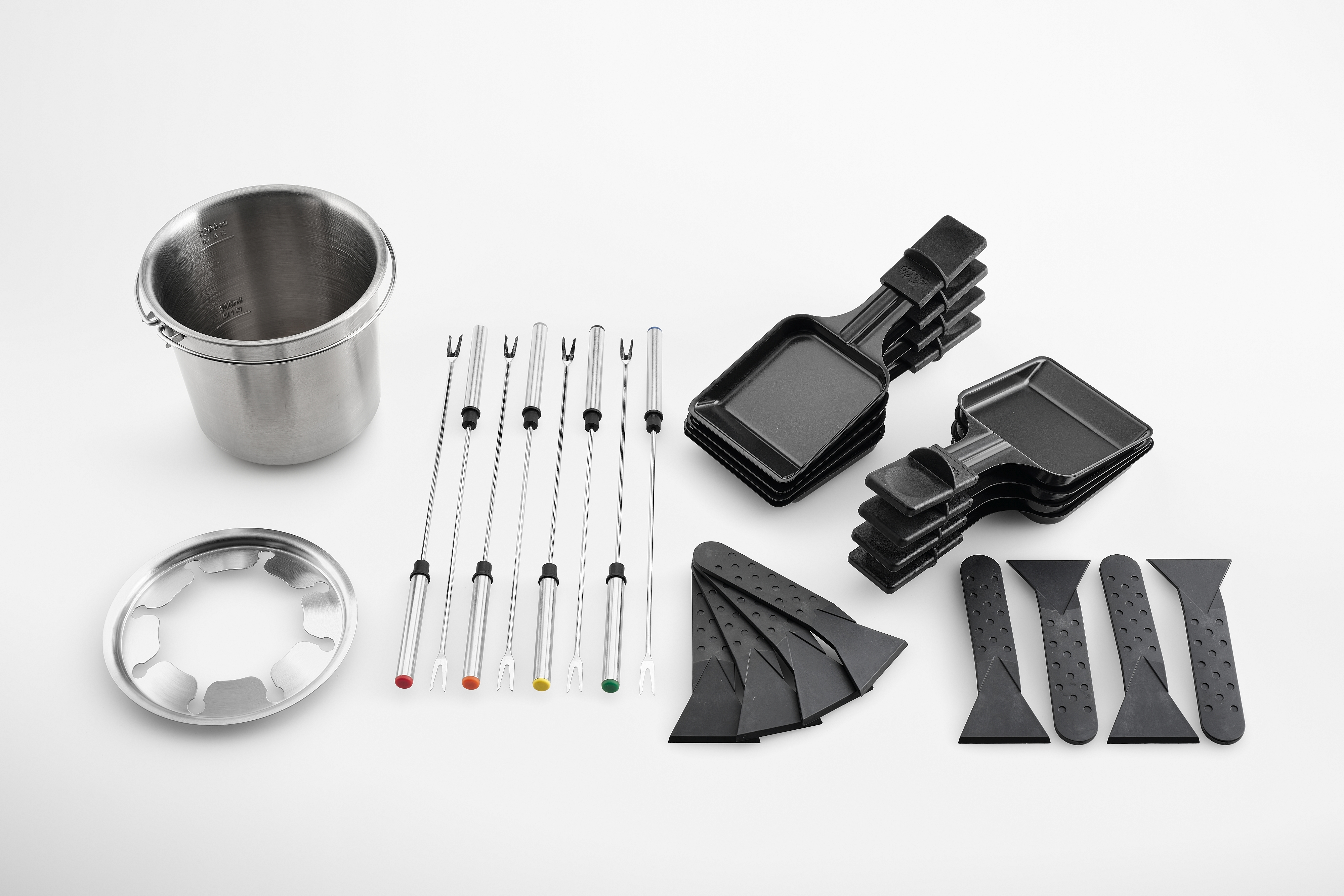 Elementy zestawu do raclette: garnek ze stali nierdzewnej, widelce, patelnie i czarne szpatułki na białej powierzchni.