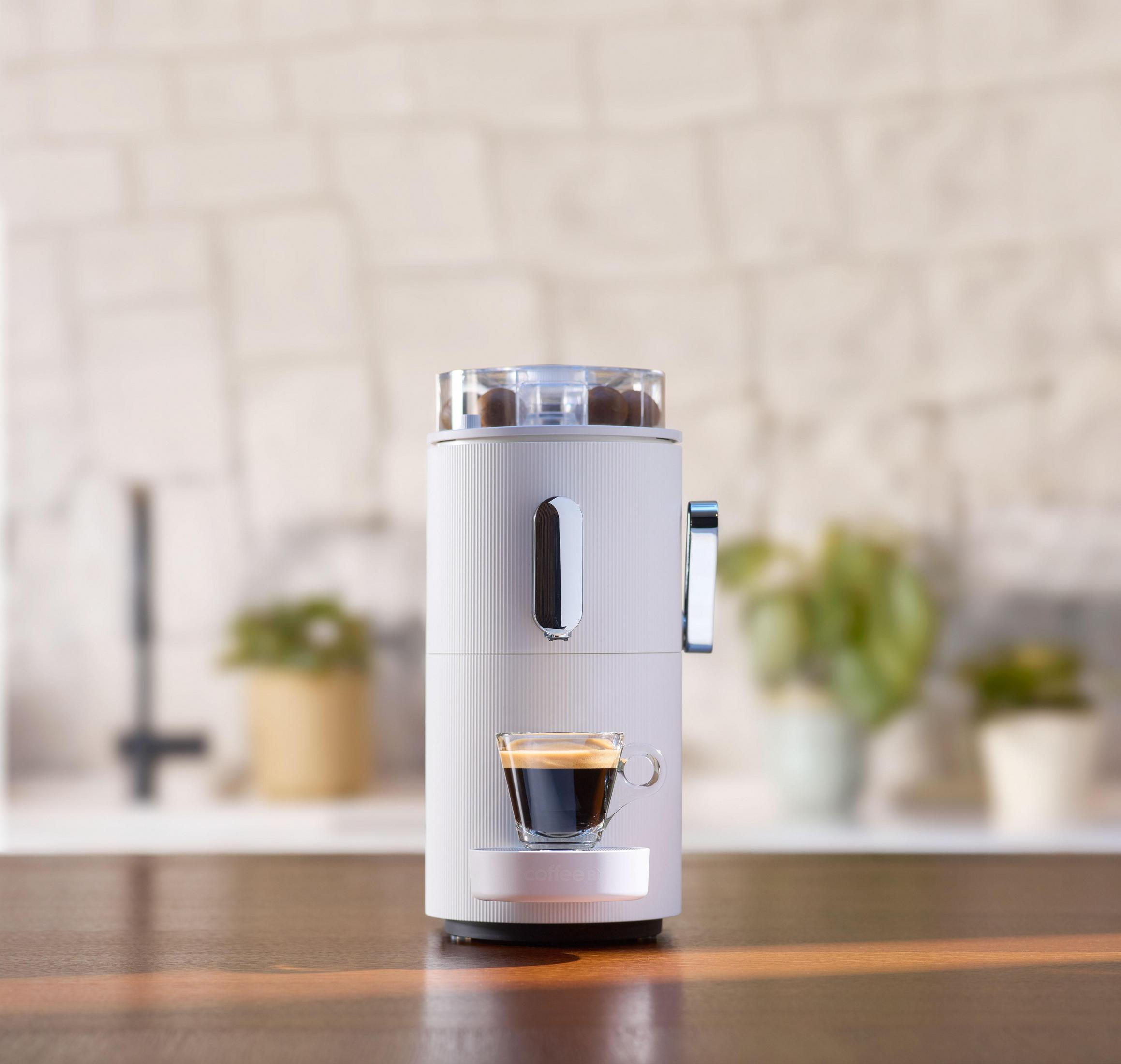 Weiße und graue Kaffeemaschine mit Espresso. Holztisch, verschwommener Hintergrund.