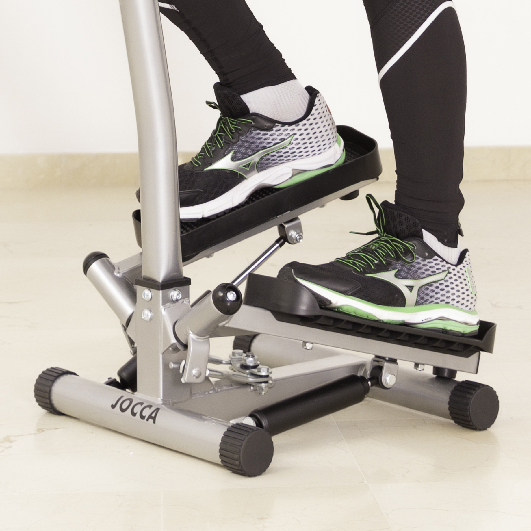 I piedi di una persona con scarpe da ginnastica su una macchina per stepper. La macchina è argento e nera.