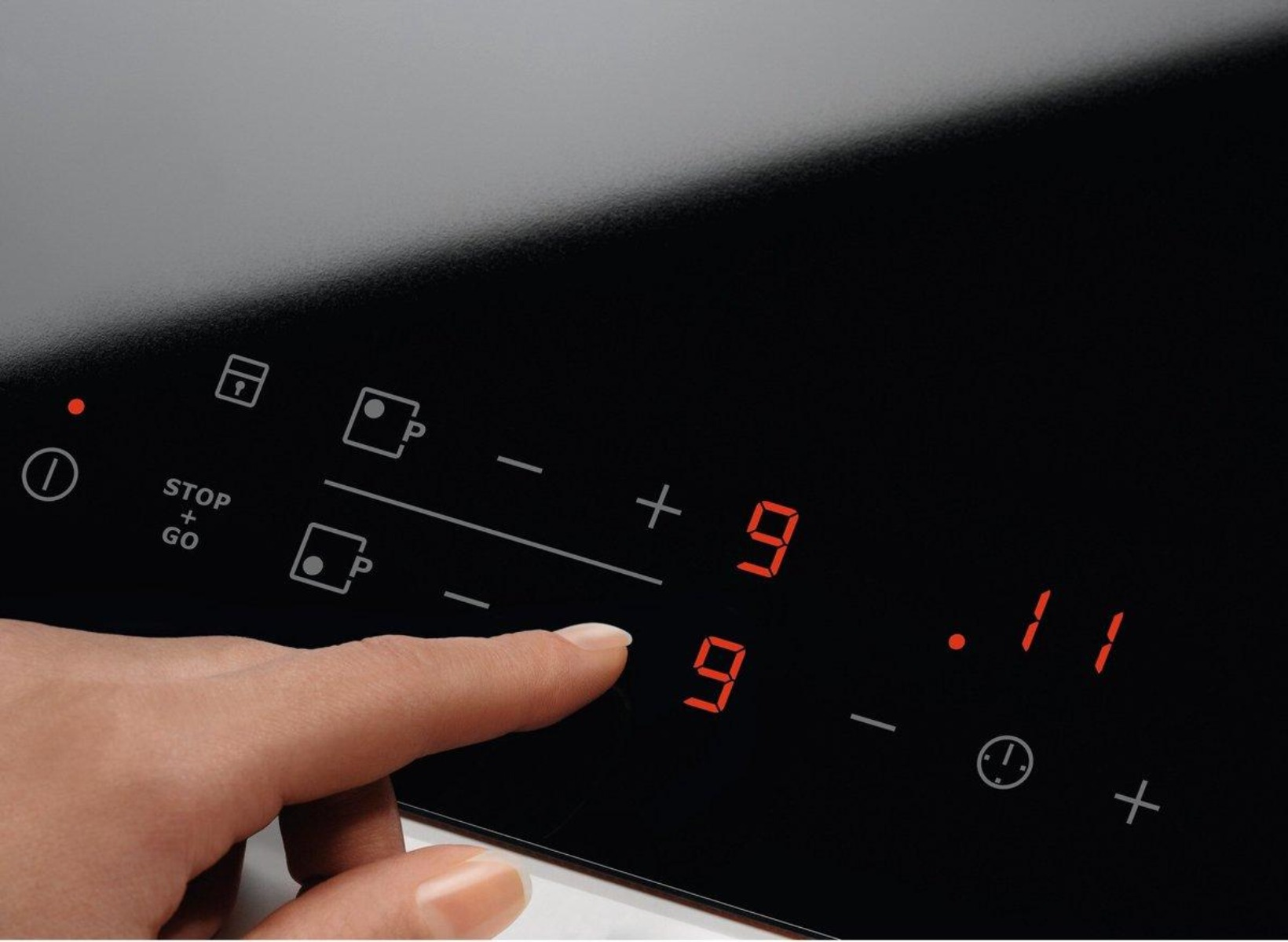 Dłoń dotyka wyświetlacza cyfrowego, liczby 9 i 11 podświetlone na czerwono.