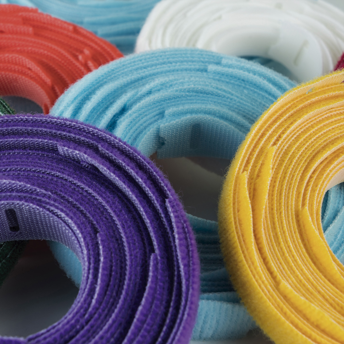 Cinghie in velcro arrotolate in più colori: viola, rosso, giallo, bianco, blu e verde.