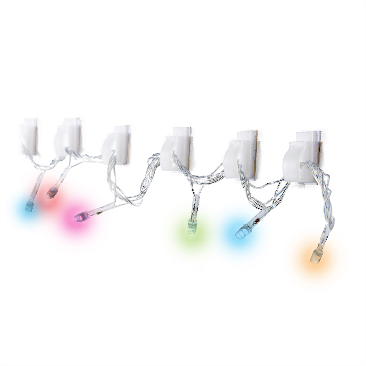 Weiße Clips mit bunten Lichtern, an einer weißen Wand befestigt. Die Lichter sind blau, rosa, grün und orange.