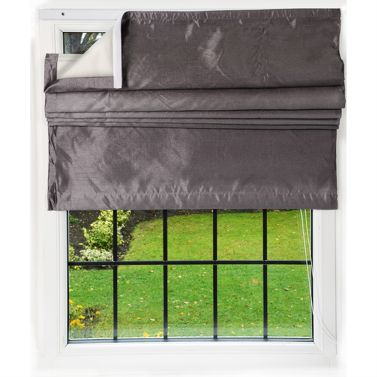 Fenster mit grauem Rollo, offen, um einen grünen Rasen und Bäume zu zeigen. Weißer Rahmen.