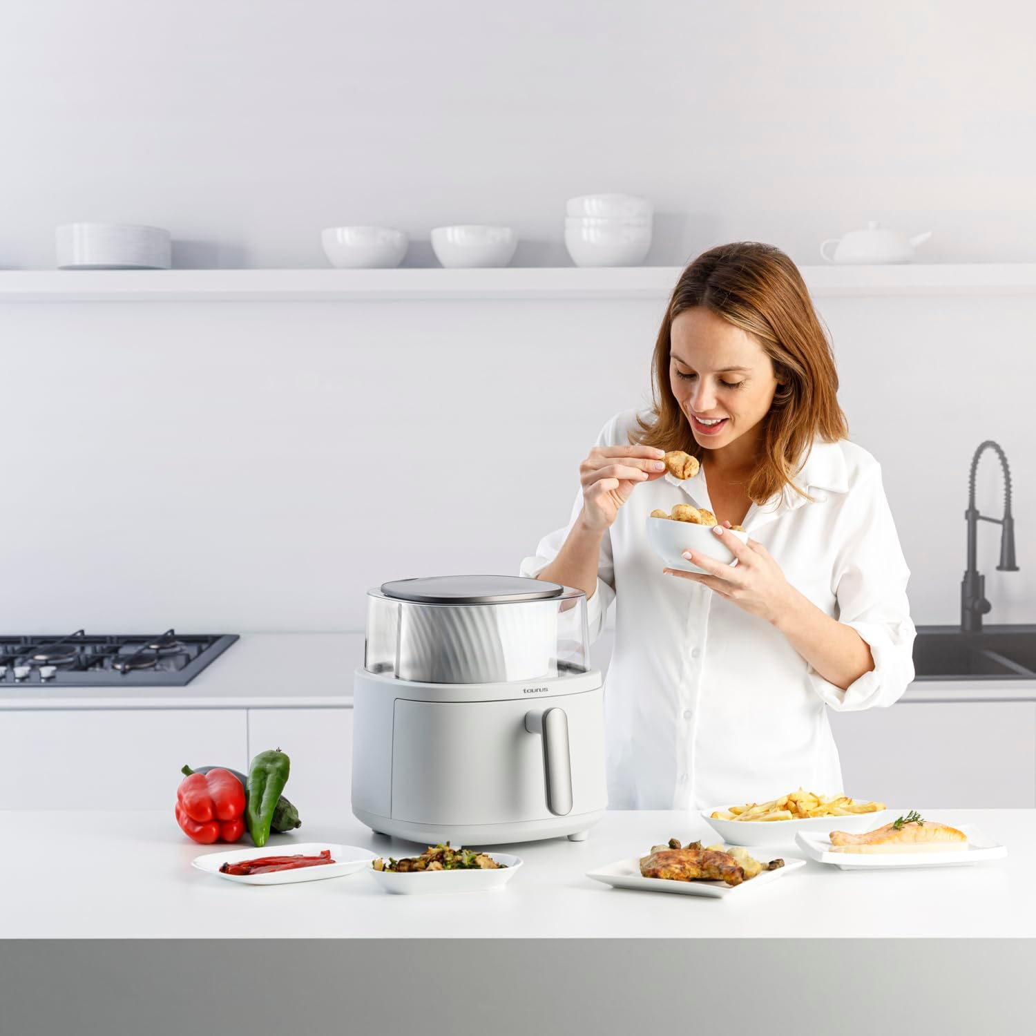 Una mujer comiendo comida frita de un cuenco. Fondo de cocina blanco.