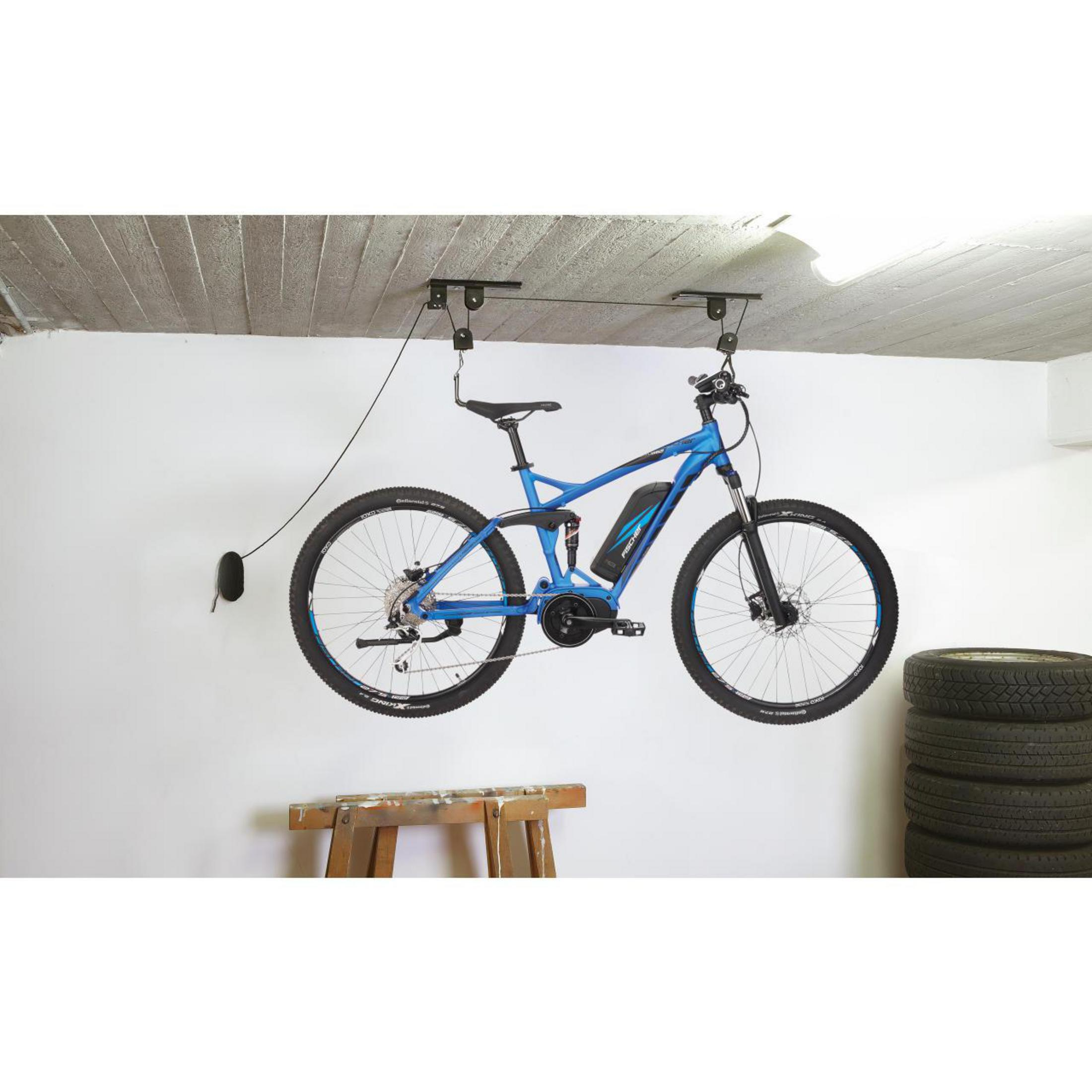 Blaues Fahrrad von der Decke abgehängt, Reifen rechts gestapelt. Garagenumgebung.