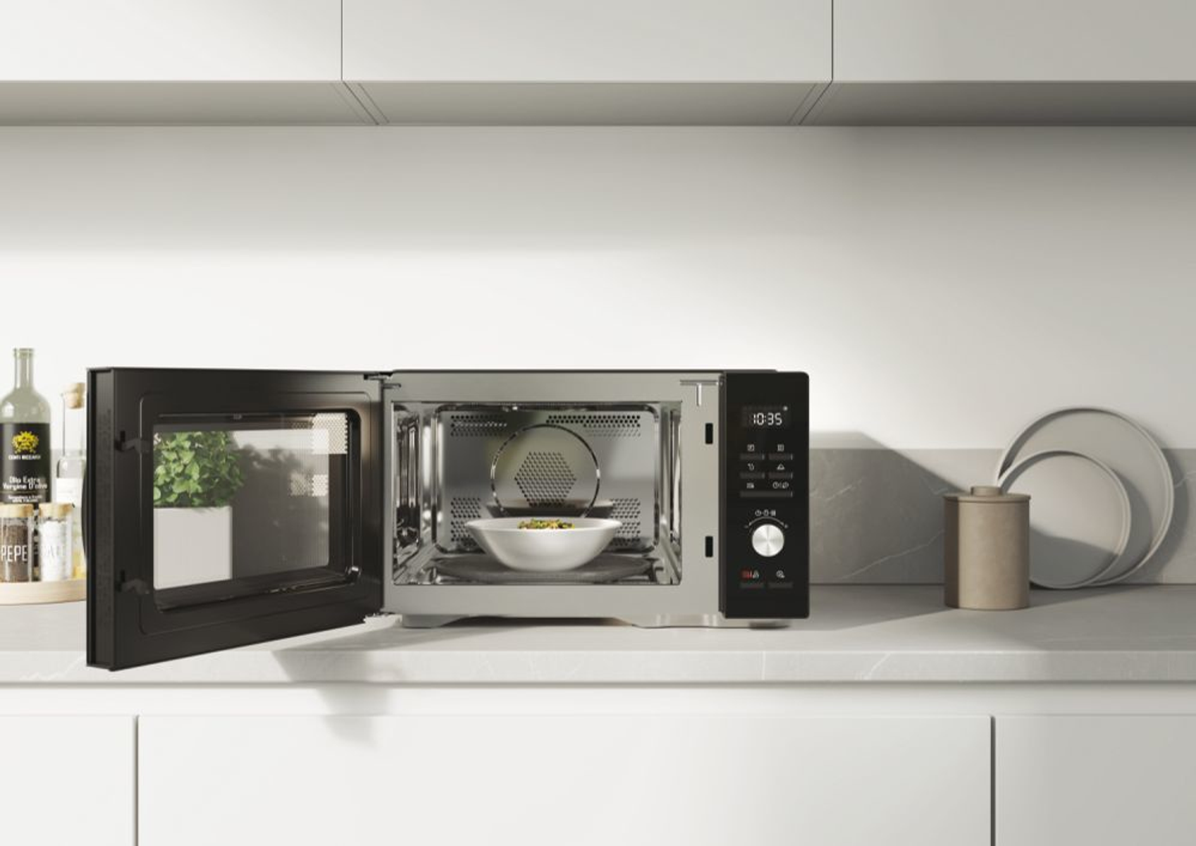 Kuchenka mikrofalowa z otwartymi drzwiami, pokazująca miskę z jedzeniem w środku, na blacie.