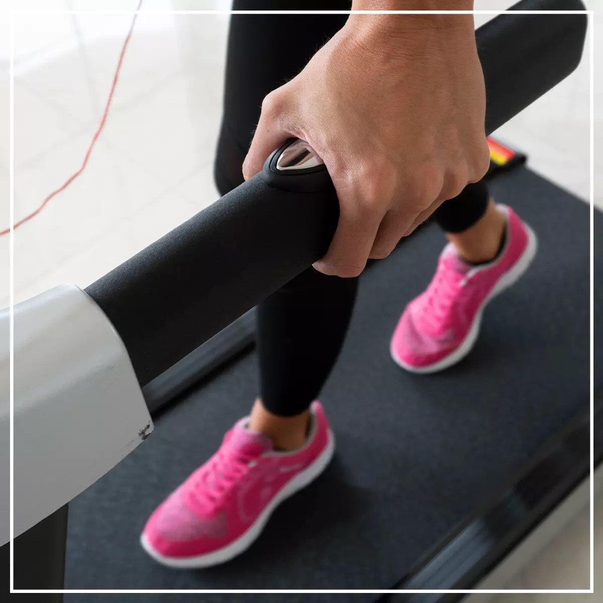 Person geht auf einem Laufband und hält eine Stange. Pinke Schuhe sichtbar. Weißer Rahmen drumherum.
