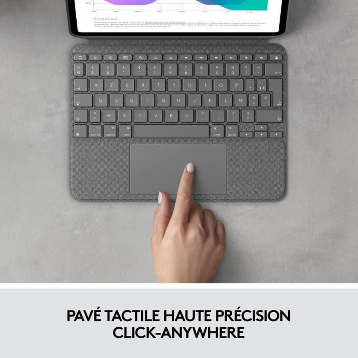 Una mano tocca il touchpad di una tastiera grigia. Un tablet mostra un grafico.
