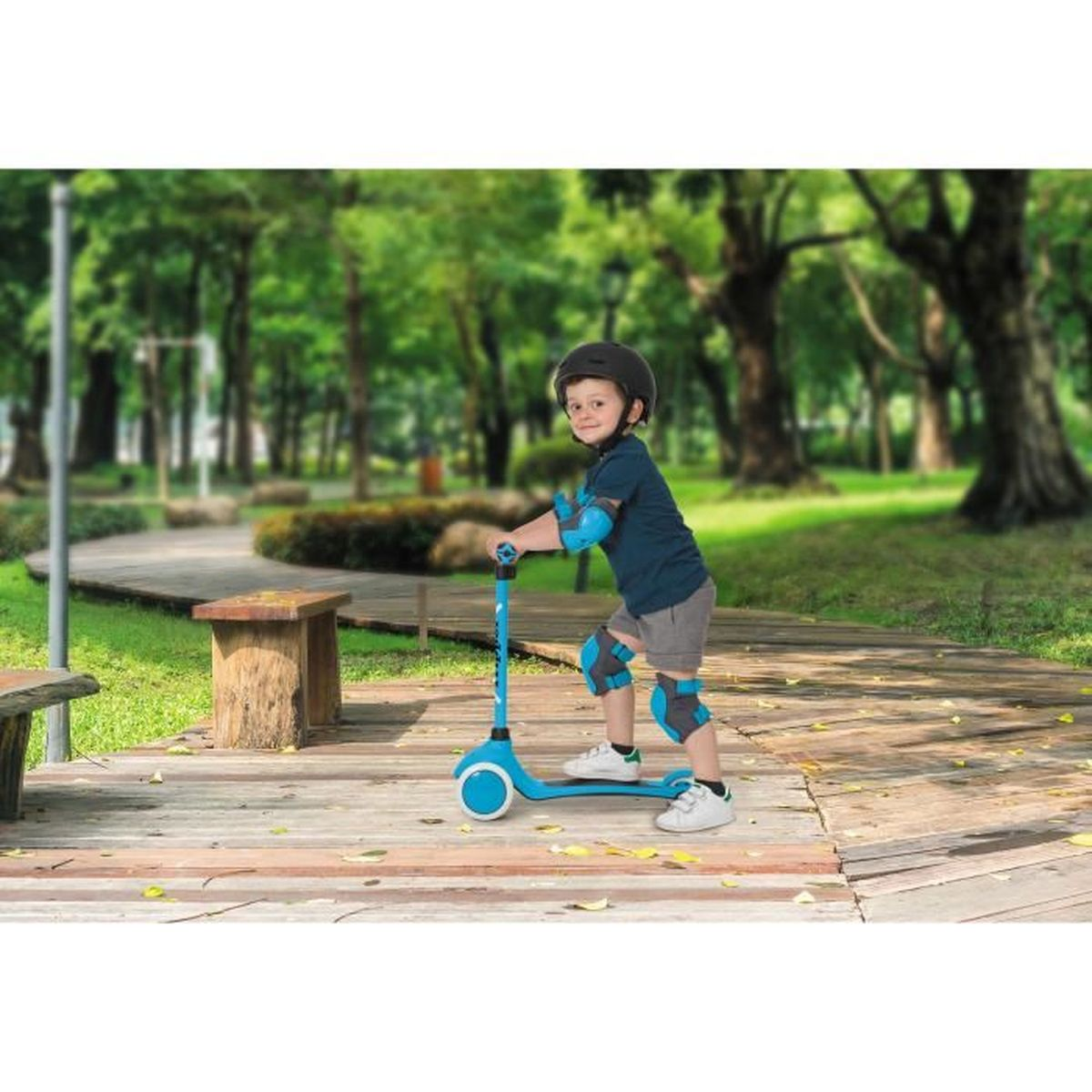 Un ragazzo su uno scooter con protezioni in un parco.