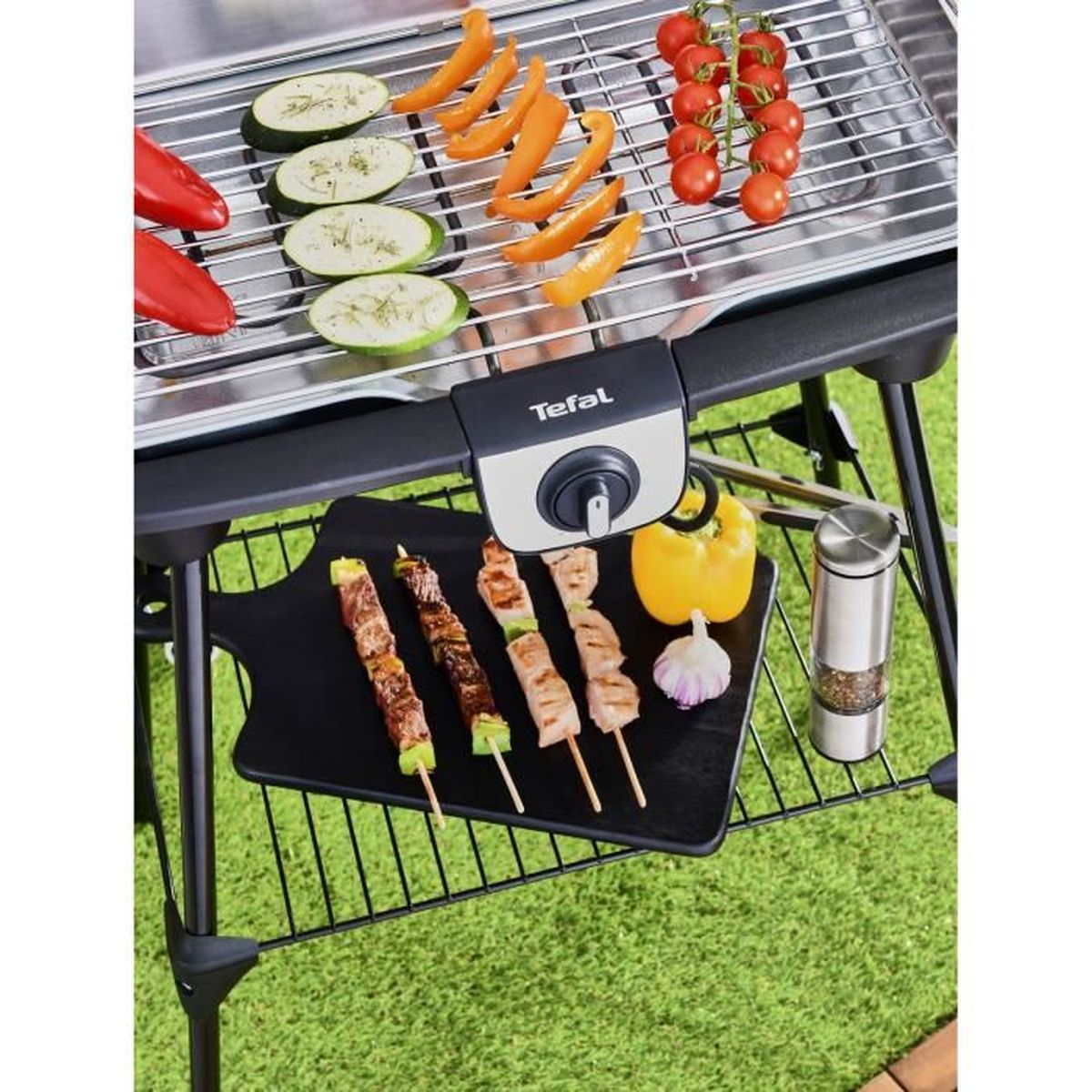 Grill mit Gemüse und Spießen. Grüner Gras Hintergrund.