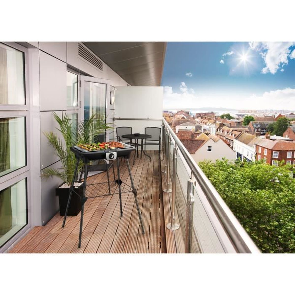 Balkon mit Grill, Tisch und Stühlen. Stadtlandschaft und blauer Himmel im Hintergrund.