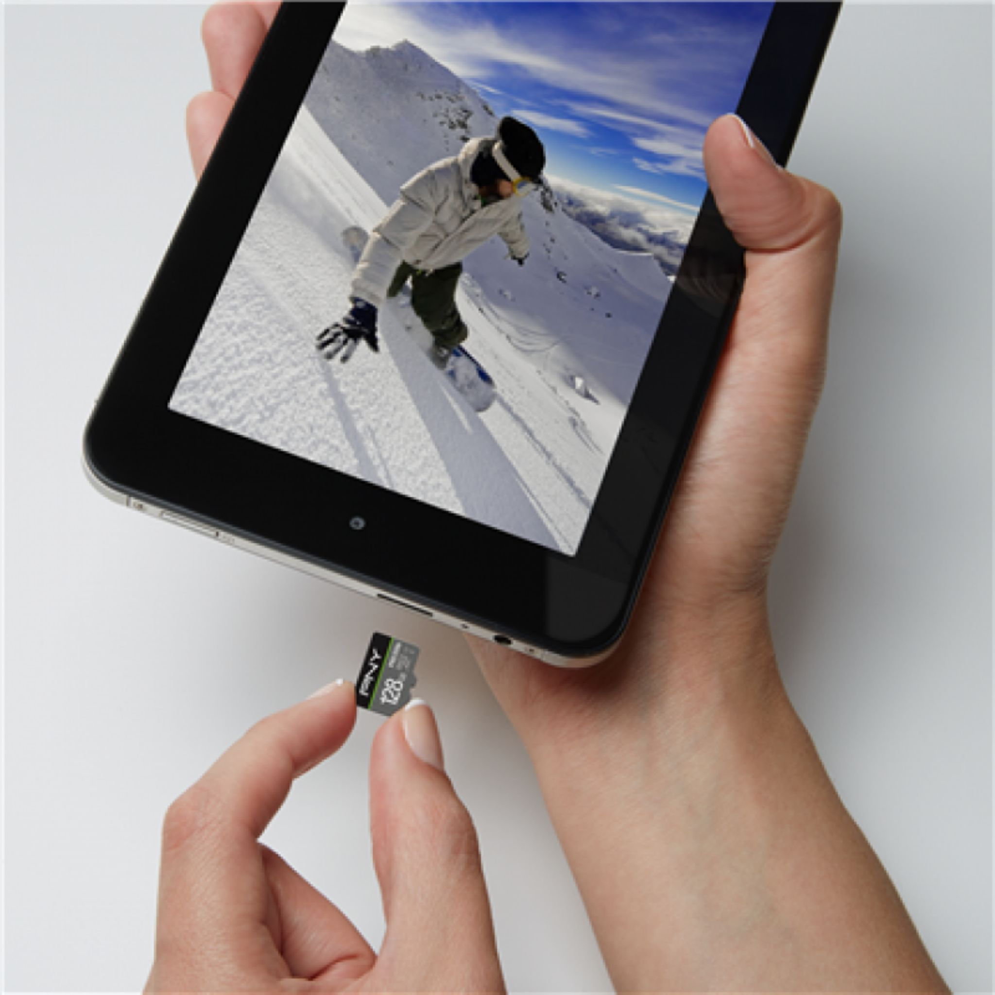 Hände halten ein Tablet mit einem Snowboarder und eine microSD-Karte.