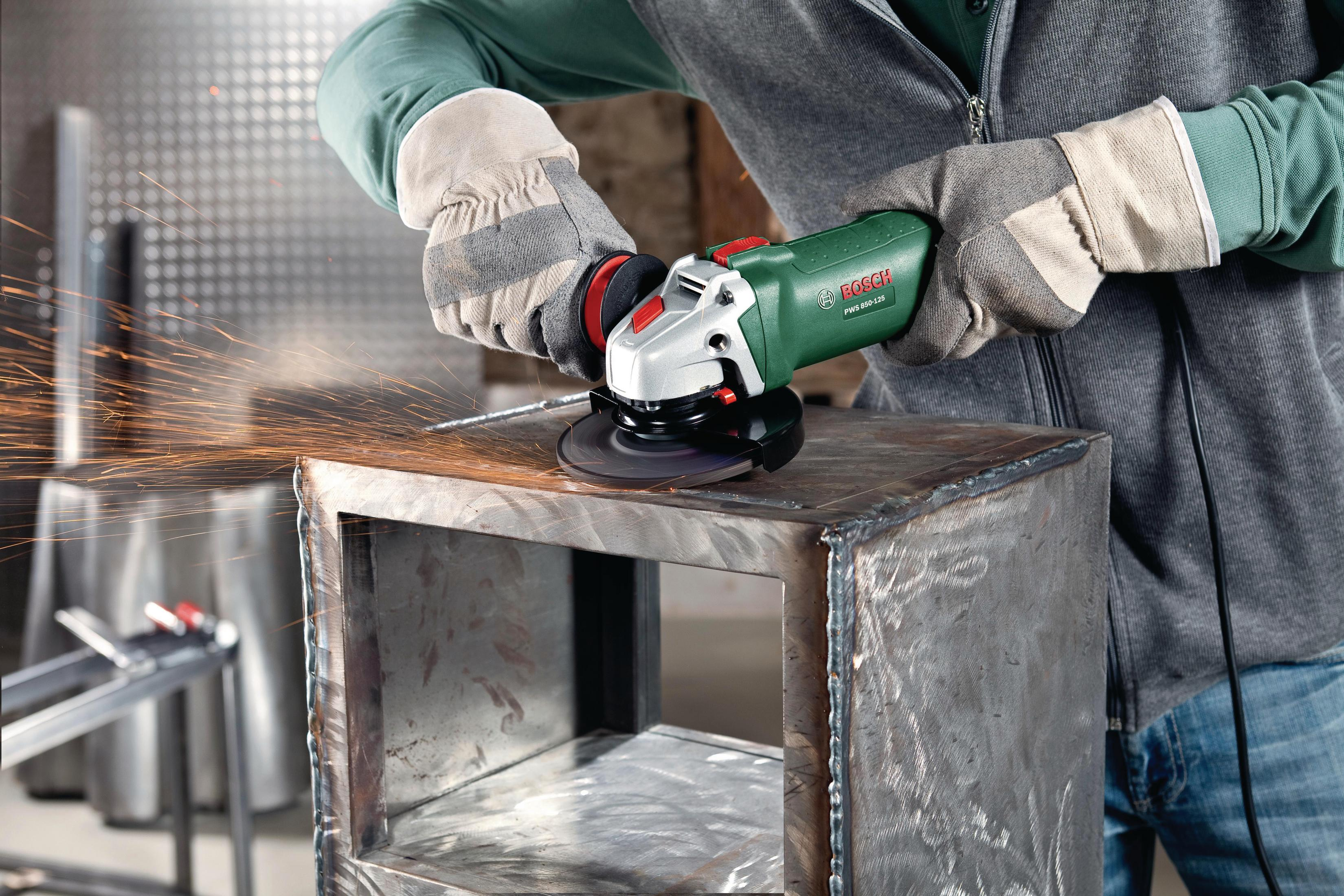 Osoba w rękawicach używająca szlifierki na metalowej skrzynce, lecą iskry.